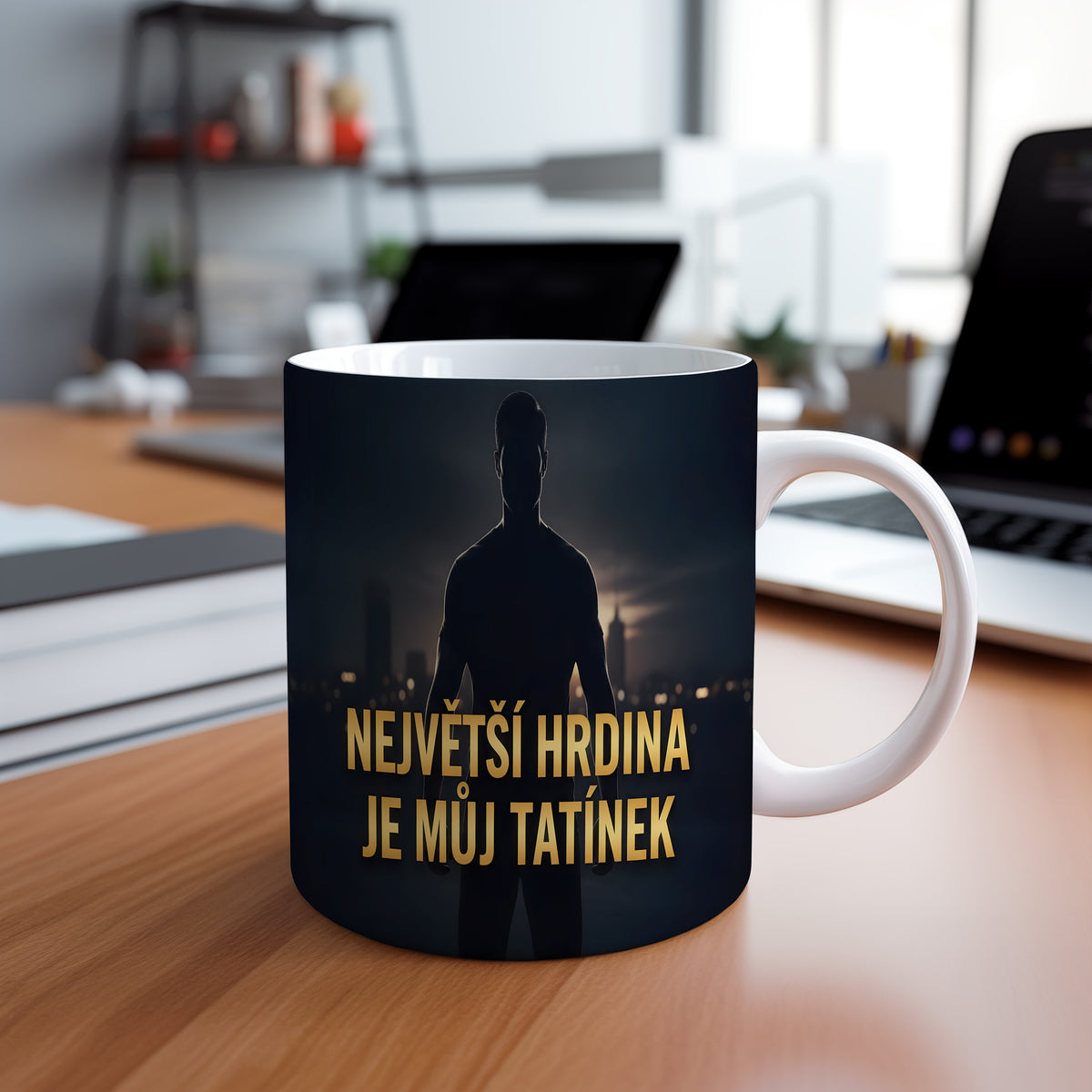 Hrnek s nápisem NEJVĚTŠÍ HRDINA JE MŮJ TATÍNEK a siluetou muže na pozadí města.