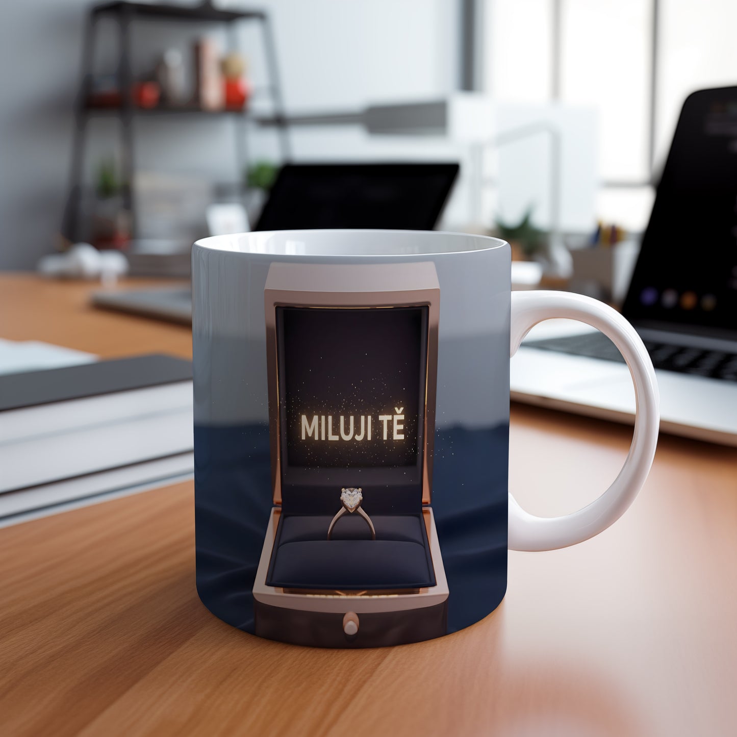 Hrnček s nápisem MILUJI TĚ a zlatým prstenem v krabičce.