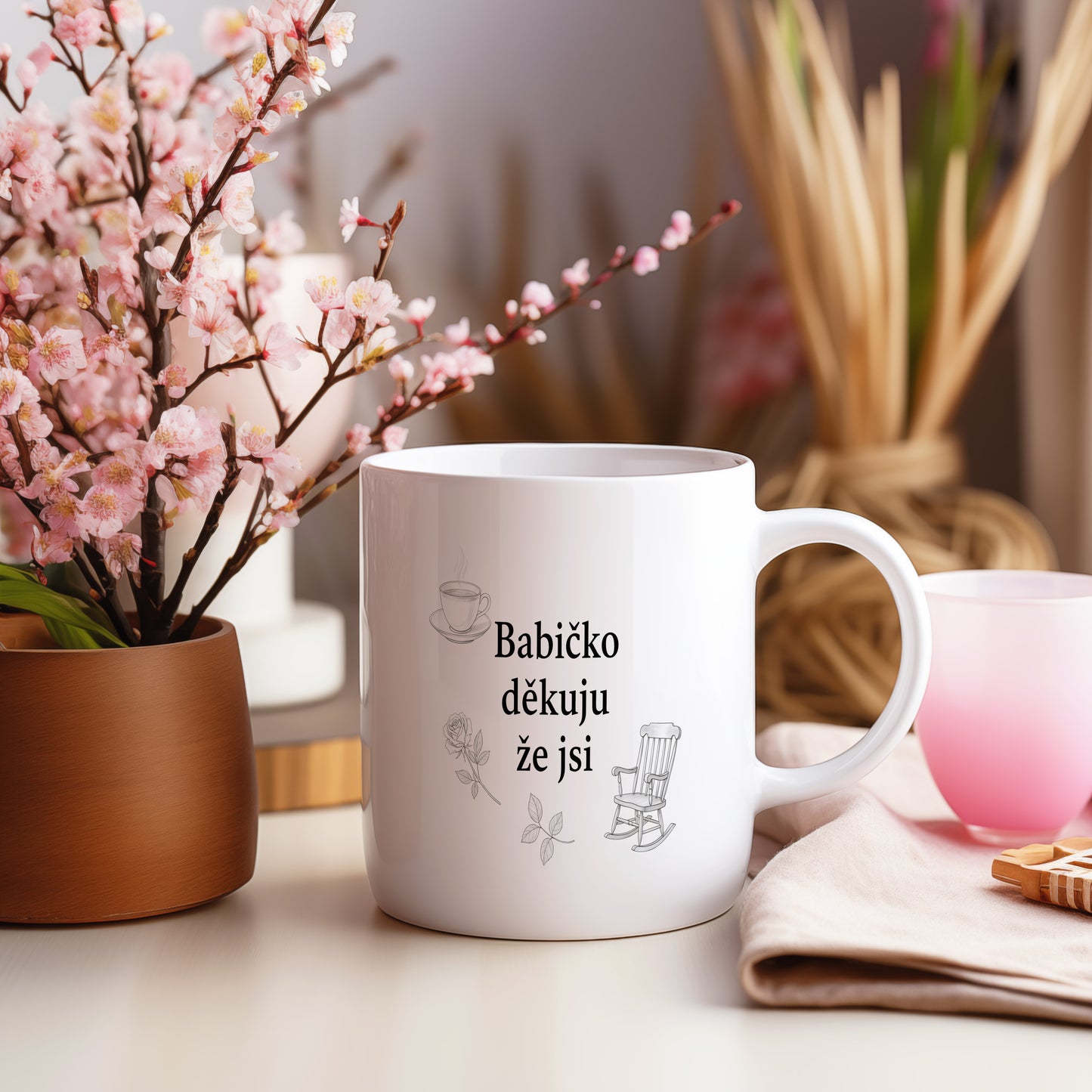 Bílý hrnek s motivy šálku kávy, růže a houpacího křesla.