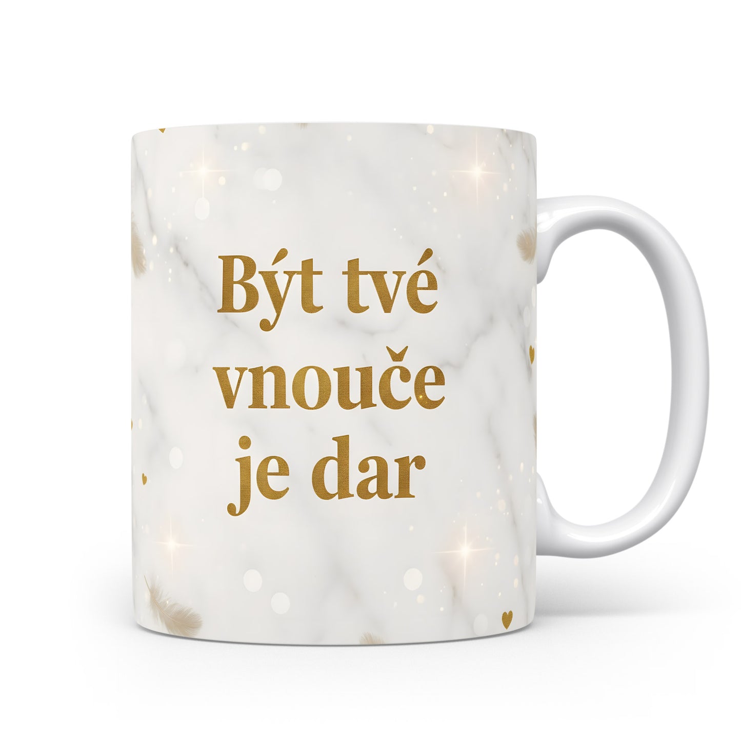 Hrnek s nápisem 'Být tvé vnouče je dar' se zlatými peříčky na mramorovém pozadí.