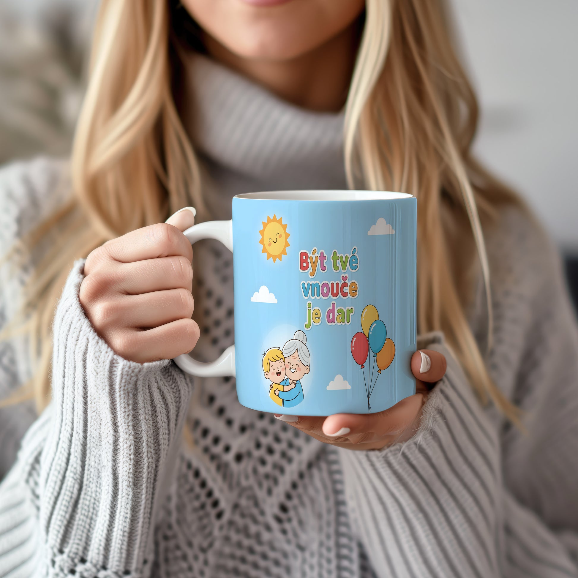 Hrnek s nápisem Být tvé vnouče je dar, sluncem a balónky na modrém pozadí.