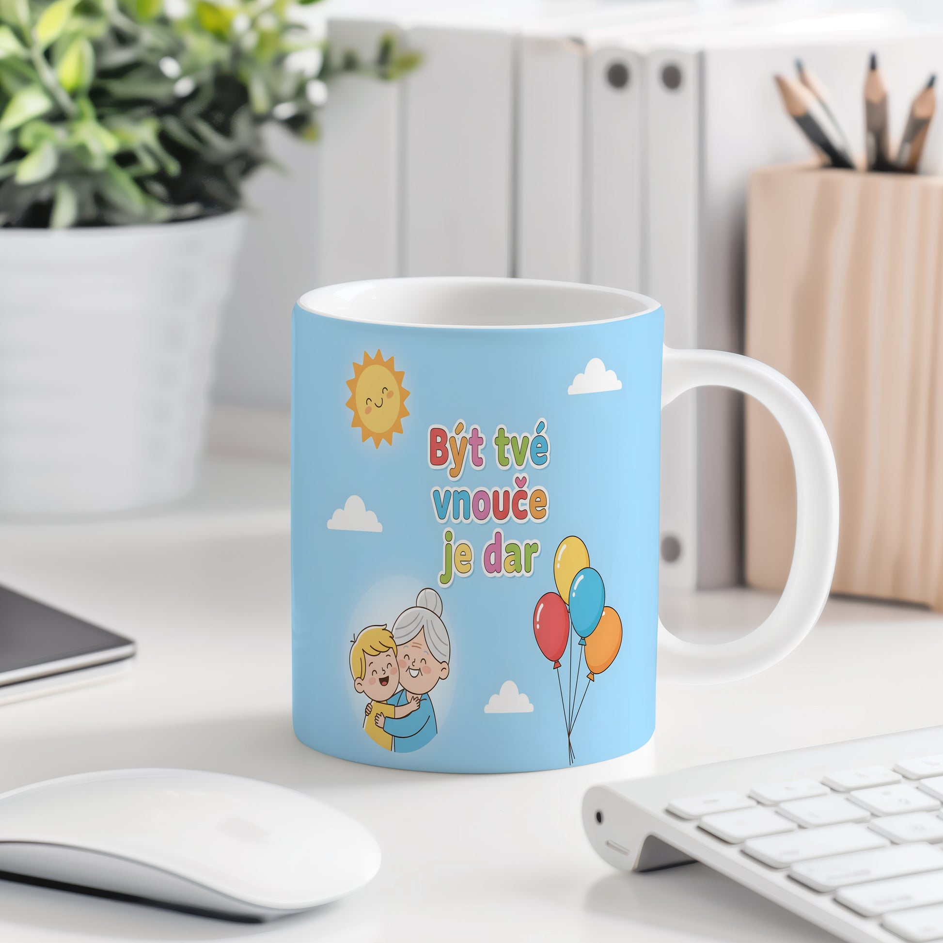Hrnek s nápisem Být tvé vnouče je dar, sluncem a balónky na modrém pozadí.