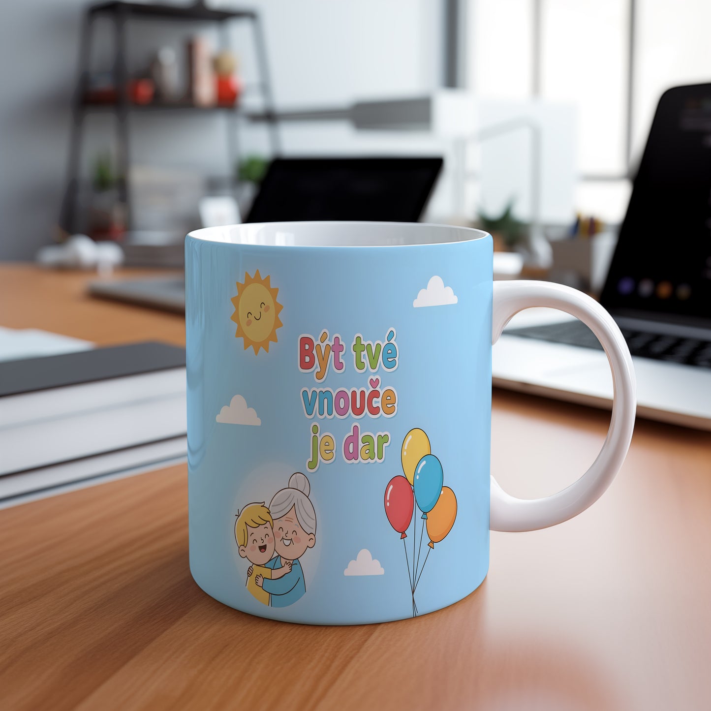 Hrnek s nápisem Být tvé vnouče je dar, sluncem a balónky na modrém pozadí.
