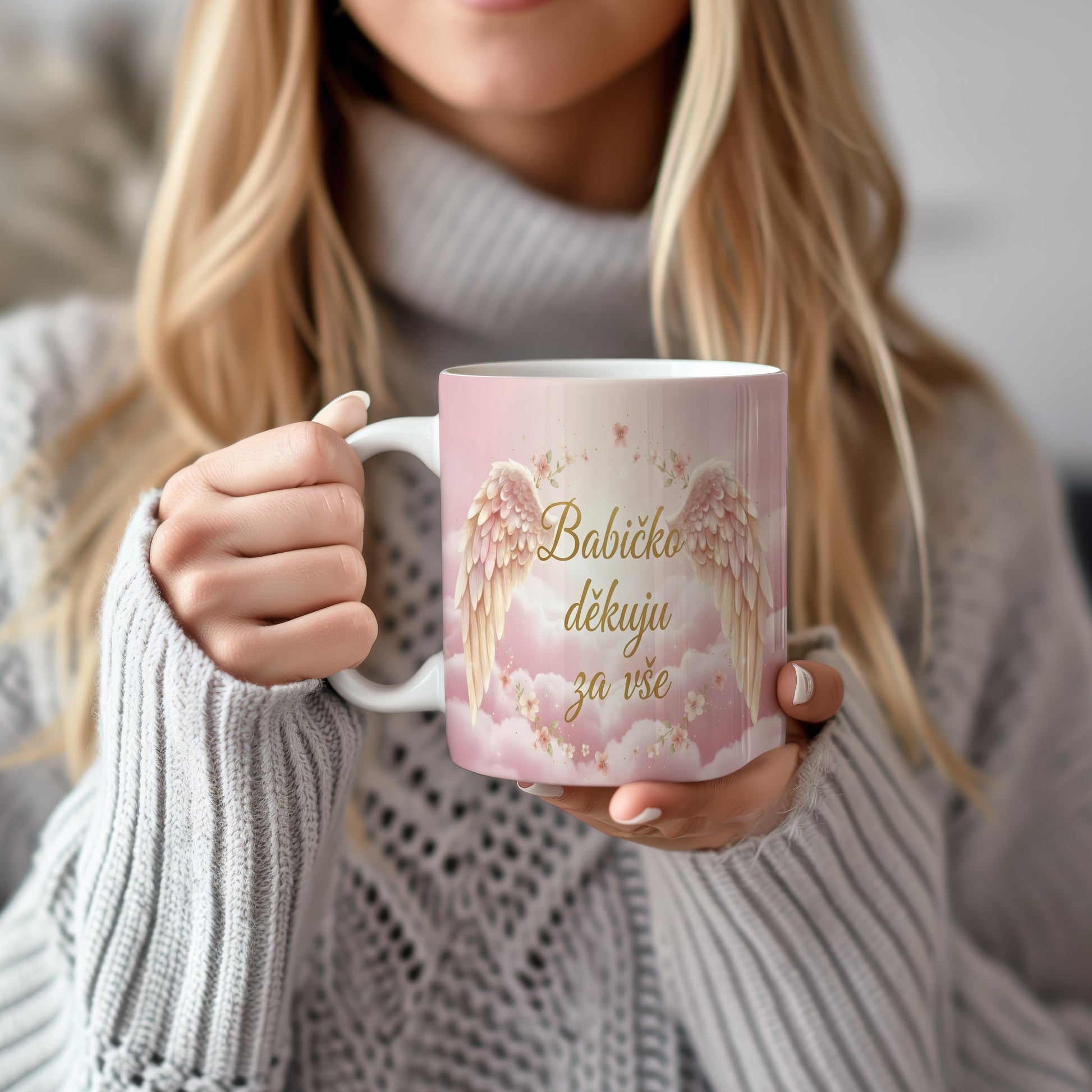 Růžový hrnek s andělskými křídly a květinami.