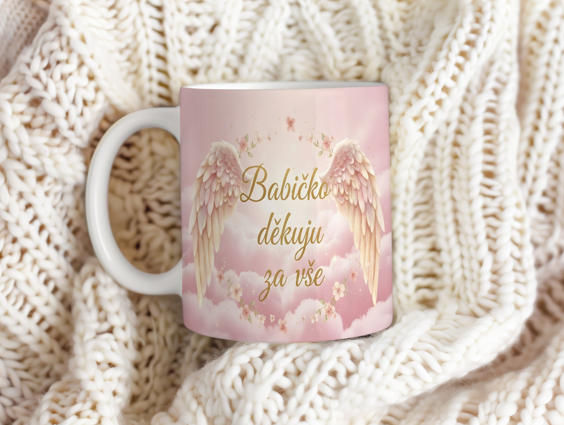 Růžový hrnek s andělskými křídly a květinami.