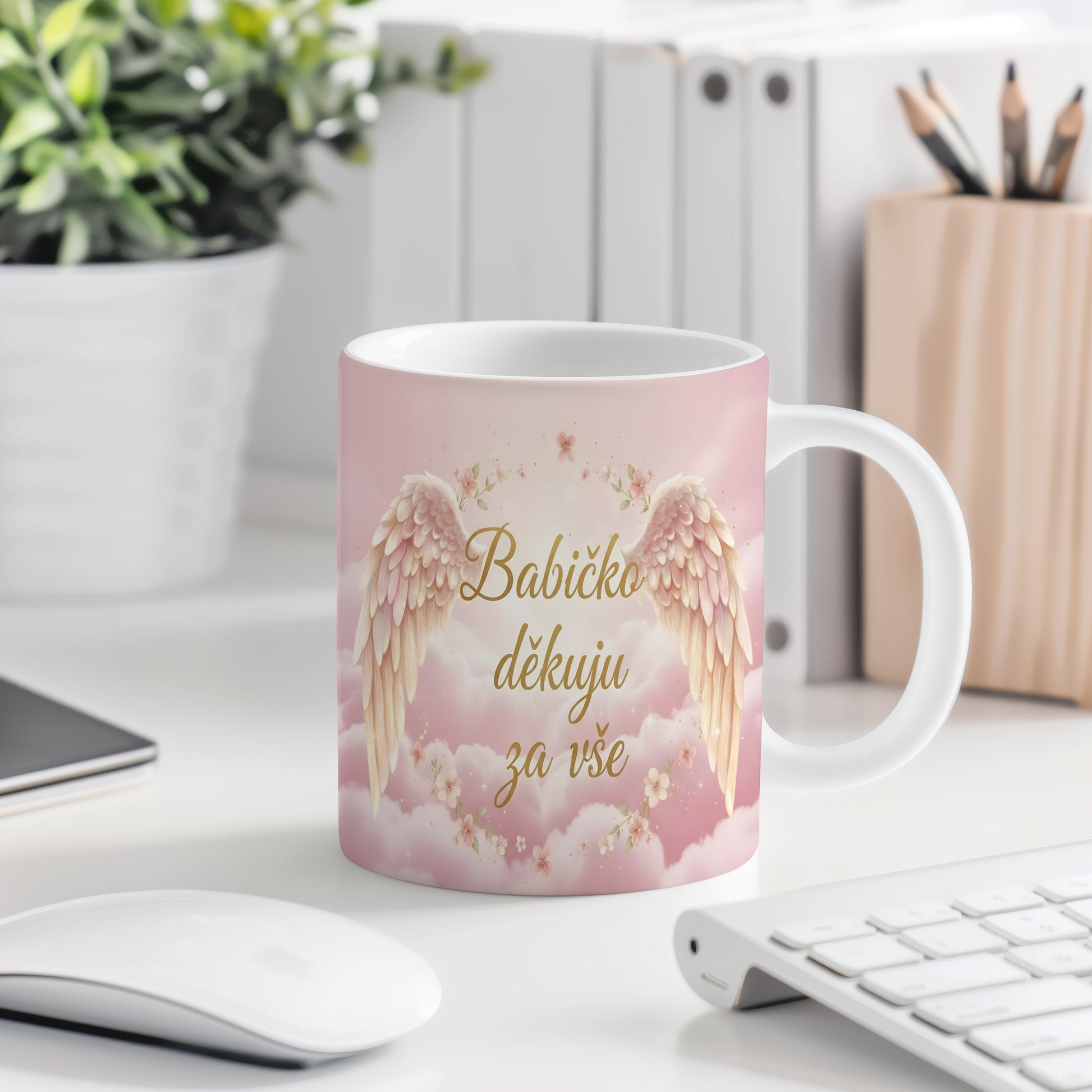 Růžový hrnek s andělskými křídly a květinami.