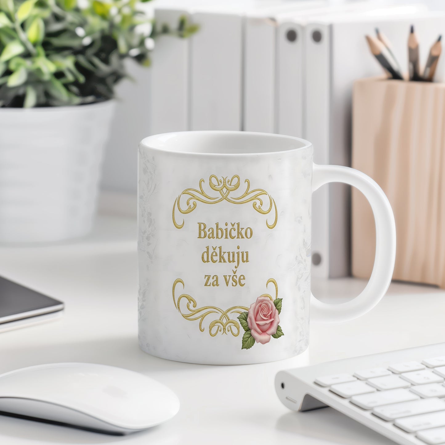 Hrnek s růžovými květy a zlatým textem na mramorovém pozadí.