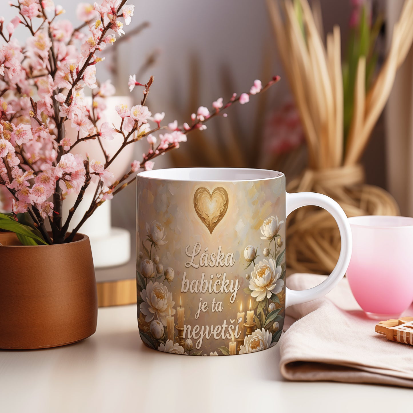 Hrnek s nápisem 'Láska babičky je ta největší', zdobený srdcem a květinami.