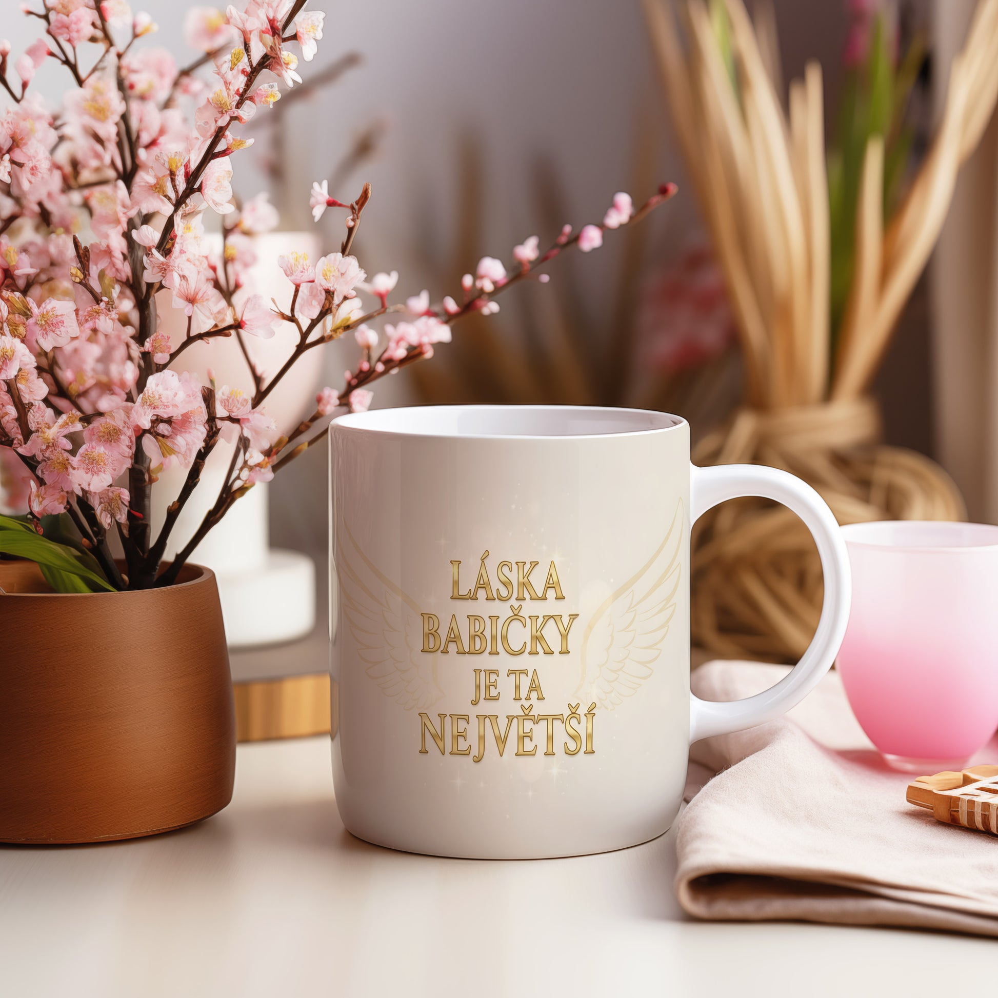 Hrnek se zlatým nápisem a křídly na světelném pozadí.