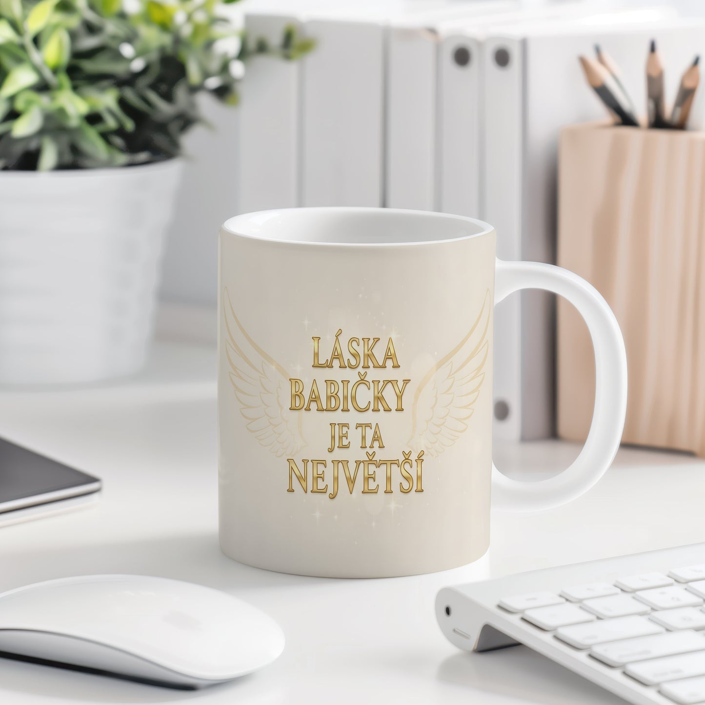 Hrnek se zlatým nápisem a křídly na světelném pozadí.