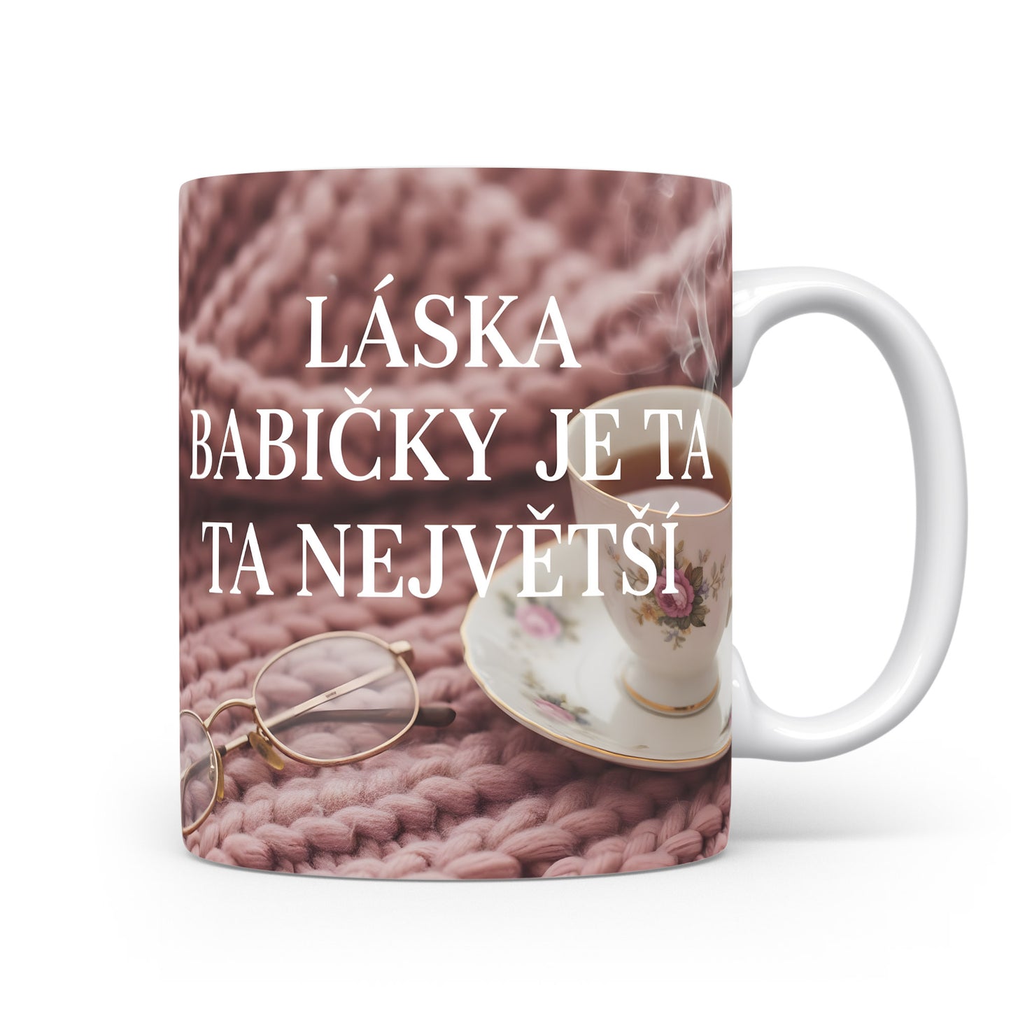 Hrnek s nápisem LÁSKA BABIČKY JE TA NEJVĚTŠÍ na růžovém pleteném pozadí.