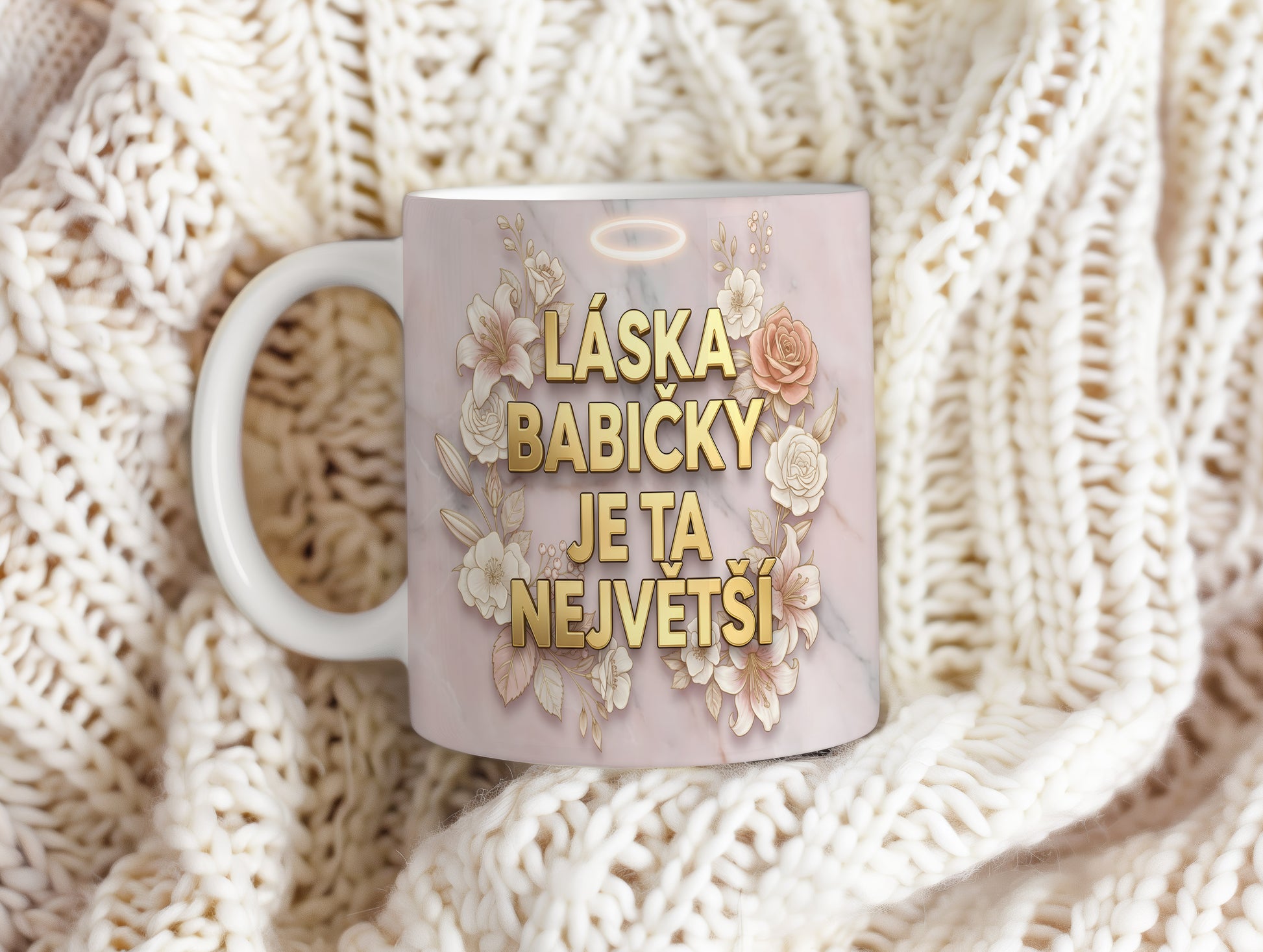 Hrnek s nápisem LÁSKA BABIČKY JE TA NEJVĚTŠÍ na mramorovém pozadí s květinami.