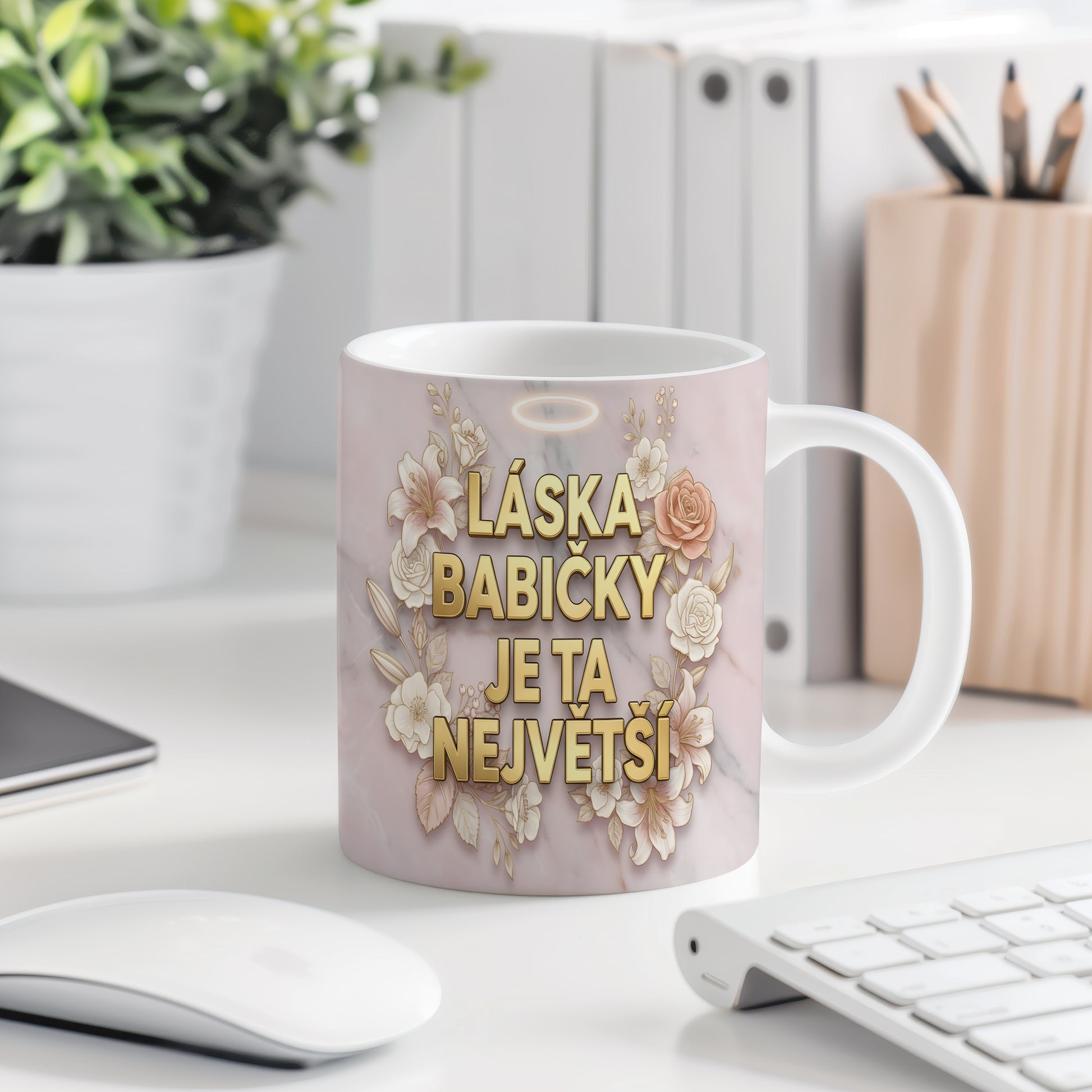 Hrnek s nápisem LÁSKA BABIČKY JE TA NEJVĚTŠÍ na mramorovém pozadí s květinami.