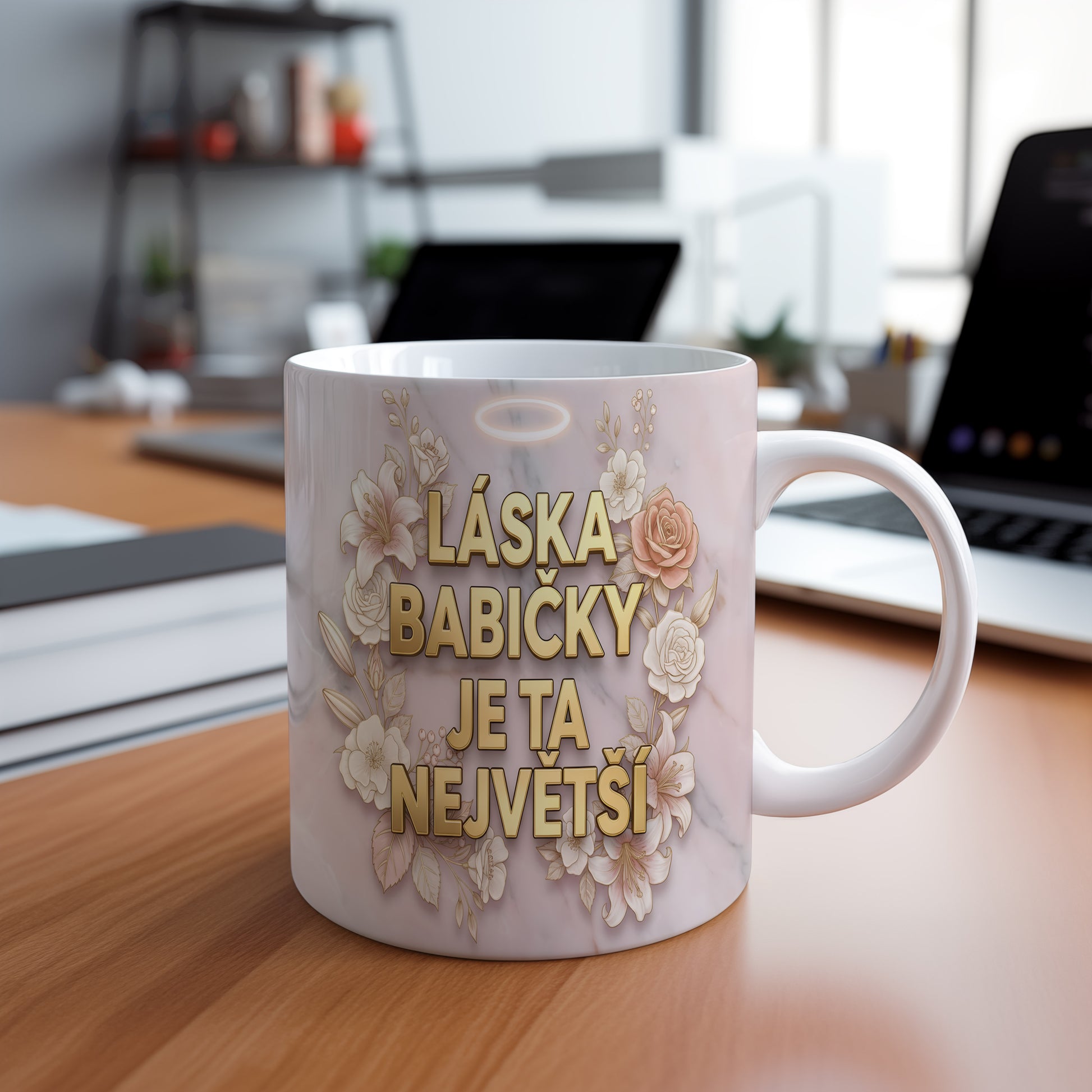Hrnek s nápisem LÁSKA BABIČKY JE TA NEJVĚTŠÍ na mramorovém pozadí s květinami.