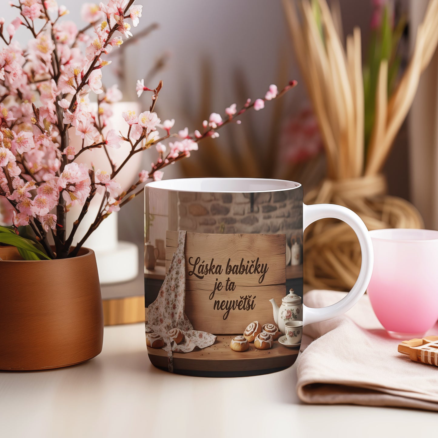 Hrnek s nápisem Láska babičky je ta největší na dřevěném pozadí s koláčky.