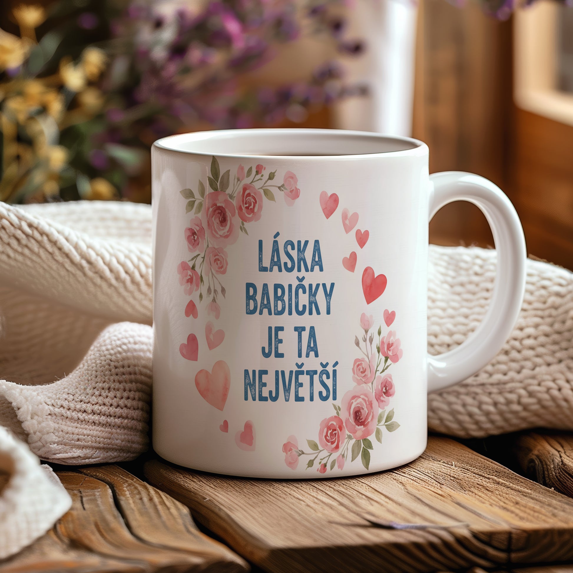 Hrnek s růžovými květy a srdíčky na pastelovém pozadí.