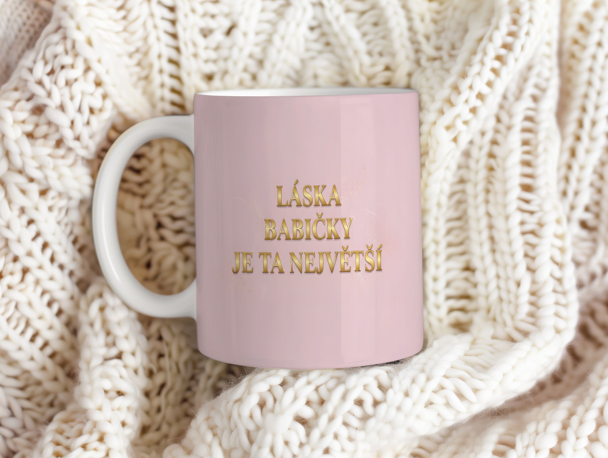 Růžový hrnek se zlatým nápisem 'LÁSKA BABIČKY JE TA NEJVĚTŠÍ'.