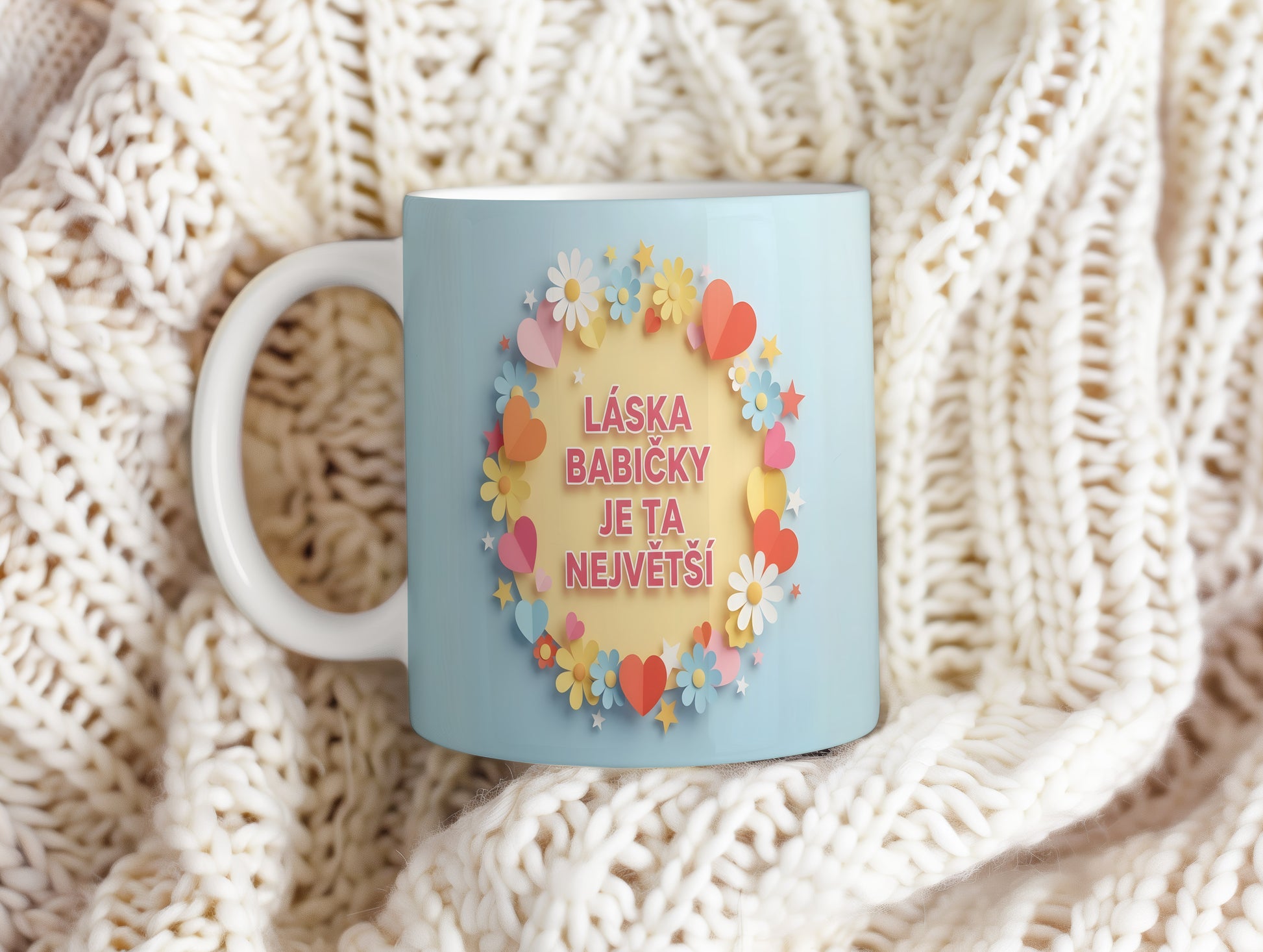 Hrnek s pastelovými květy a srdíčky na světle modrém pozadí.
