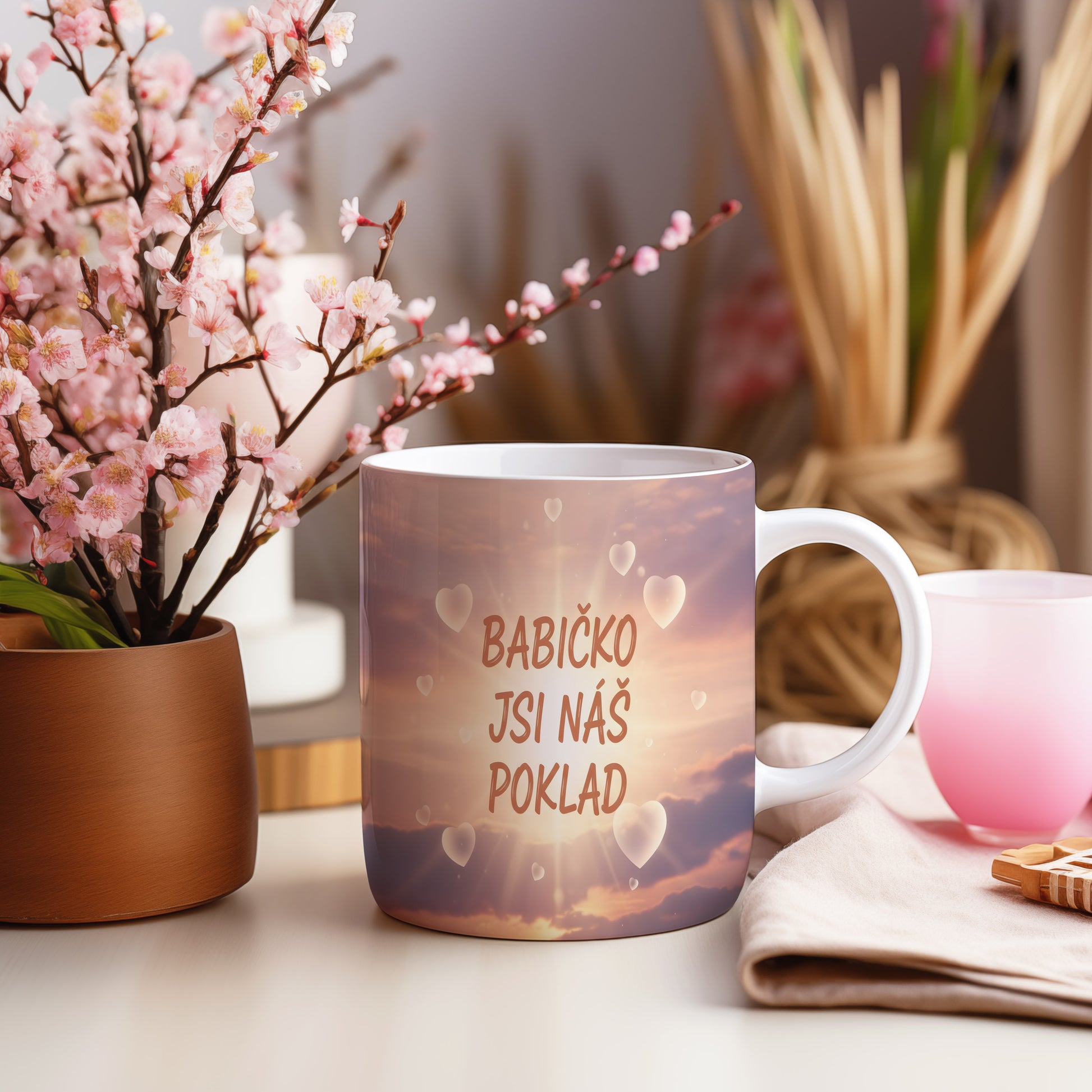 Hrnek s pastelovým pozadím a srdci s nápisem 'BABIČKO JSI NÁŠ POKLAD'.