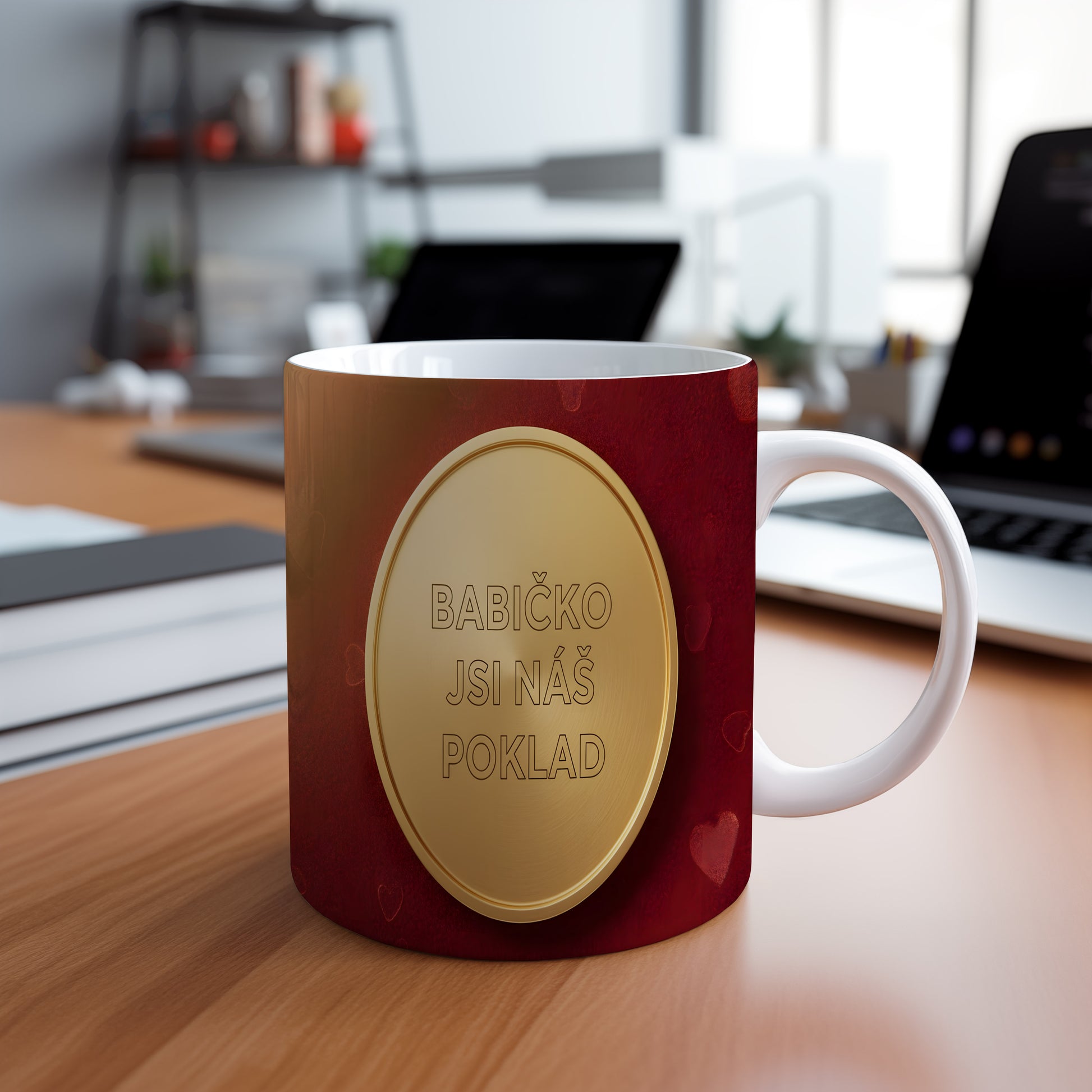 Hrnek s nápisem BABIČKO JSI NÁŠ POKLAD na červeném pozadí se zlatým medailonem.