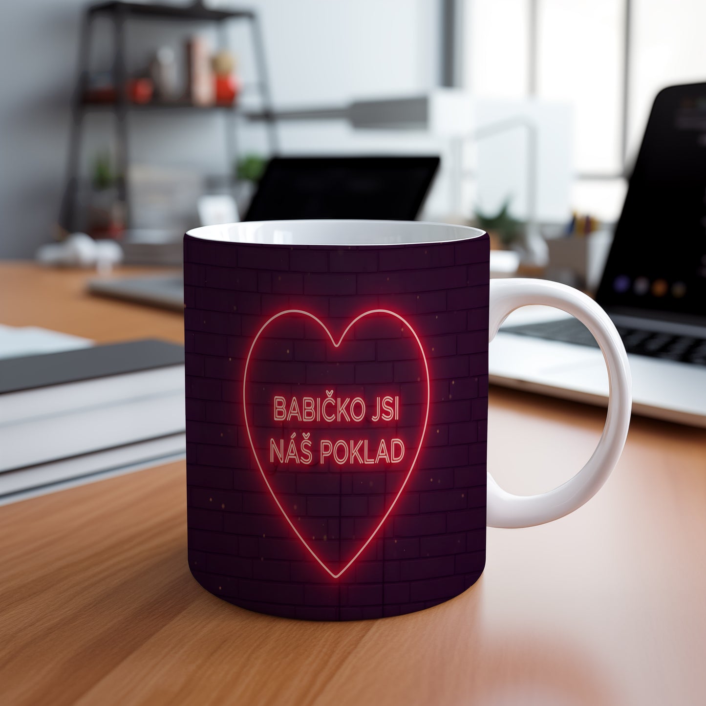 Hrnek s neonovým srdcem a nápisem BABIČKO JSI NÁŠ POKLAD na cihlovém pozadí.