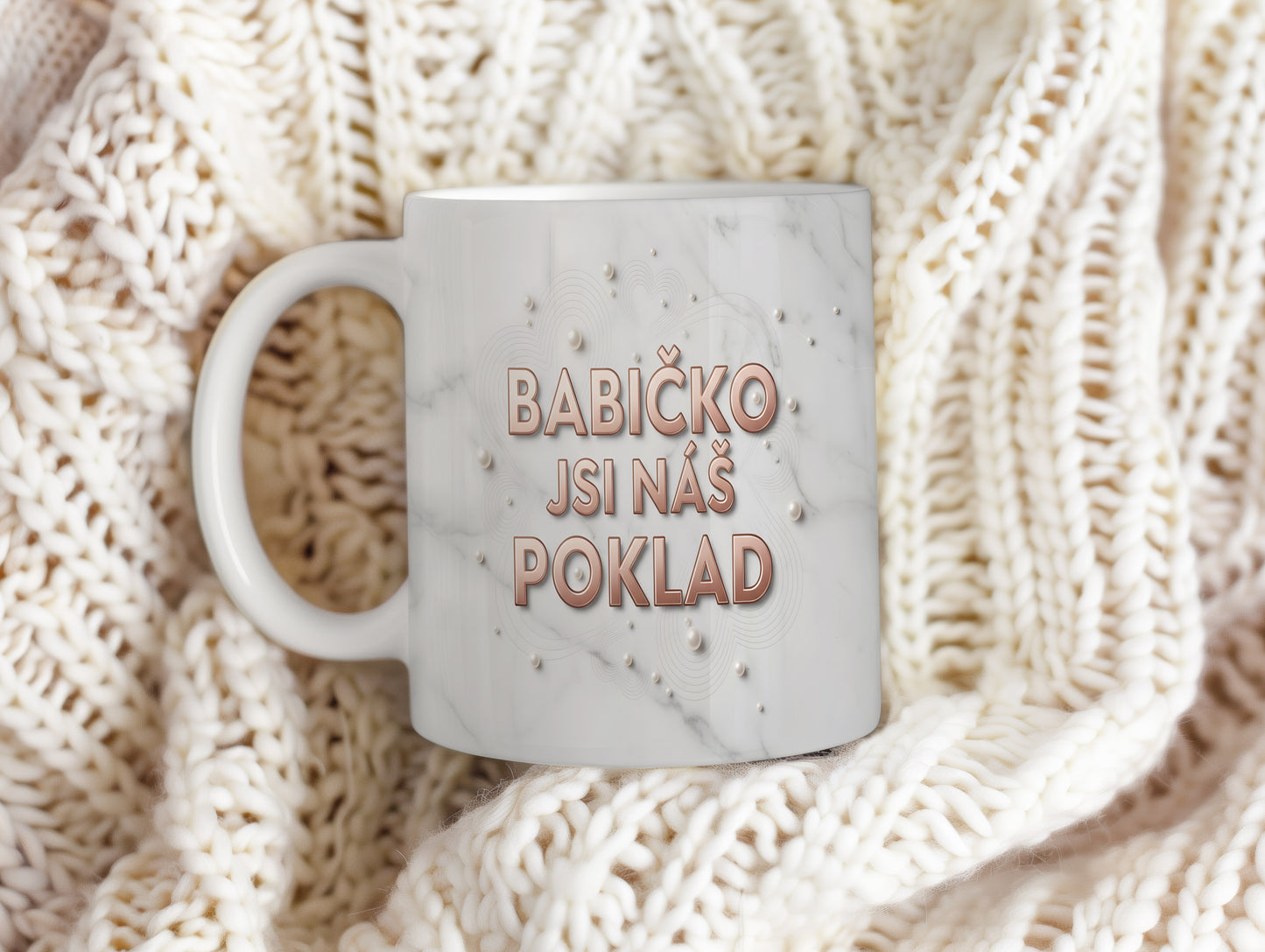 Hrnek s nápisem BABIČKO JSI NÁŠ POKLAD na mramorovém pozadí s perlami.