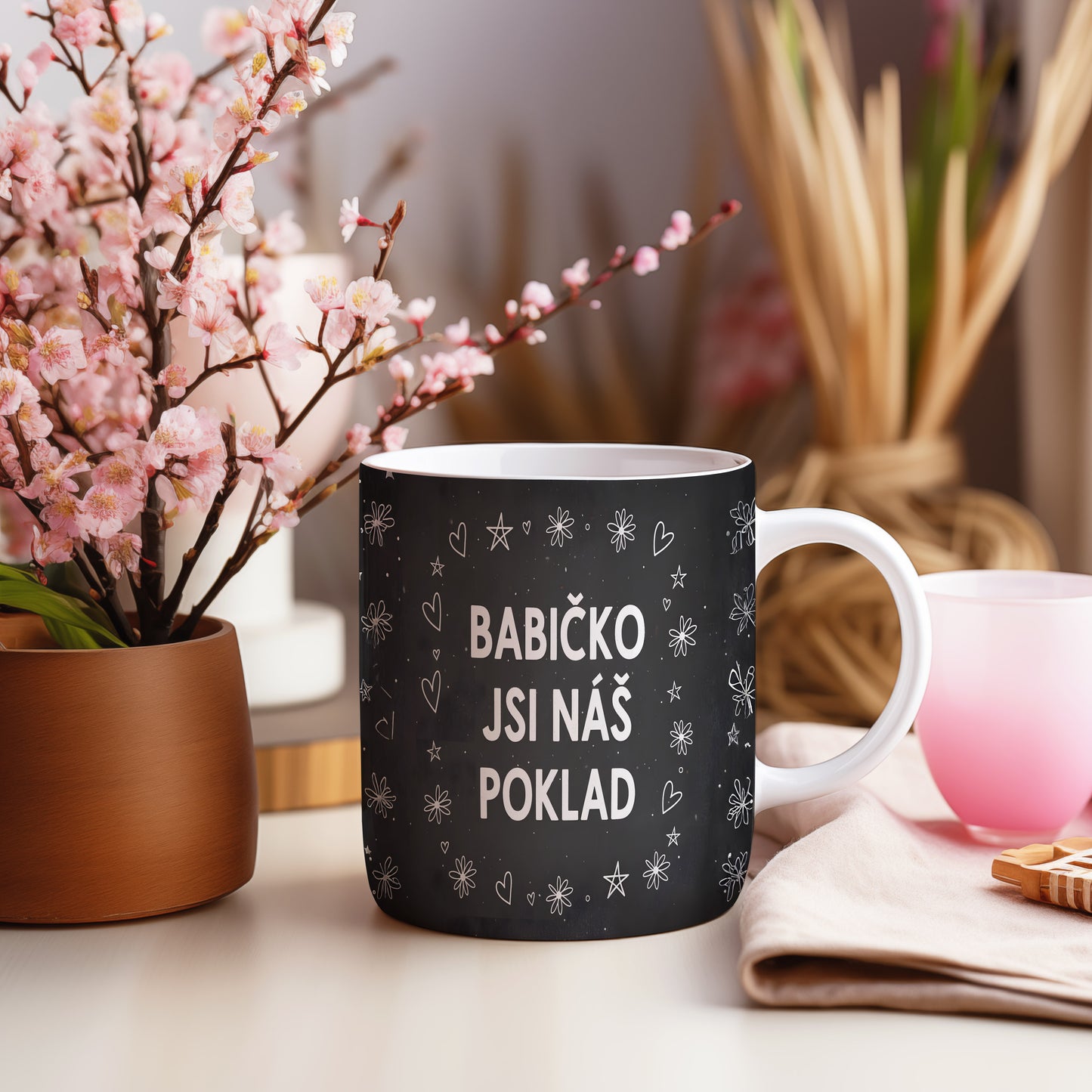 Černobílý hrnek s nápisem a motivem srdíček a květin.