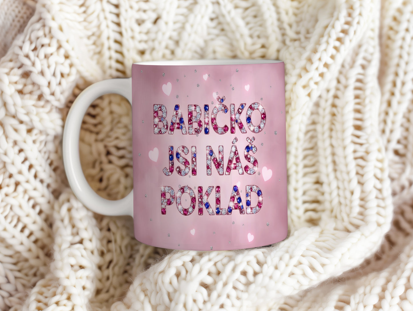 Růžový hrnek s nápisem 'BABIČKO JSI NÁŠ POKLAD' a třpytivými srdíčky.
