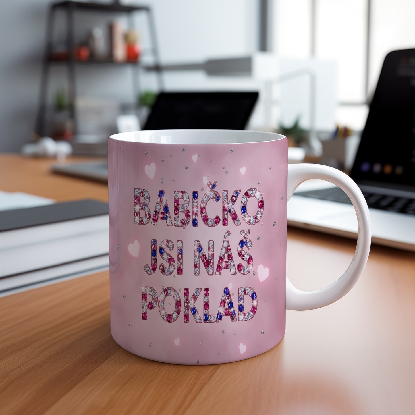 Růžový hrnek s nápisem 'BABIČKO JSI NÁŠ POKLAD' a třpytivými srdíčky.