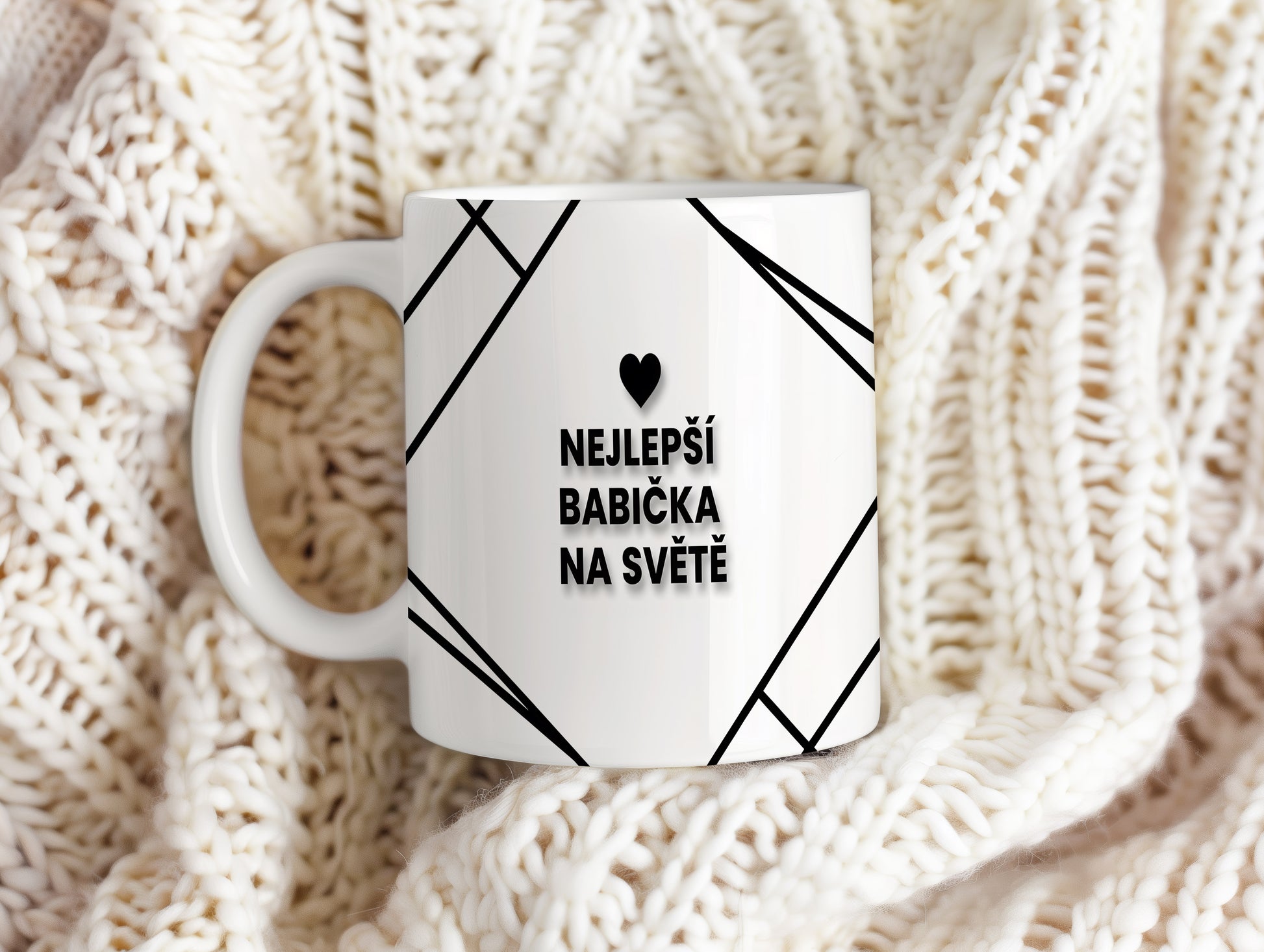 Bílý hrnek s černým nápisem a srdcem pro nejlepší babičku.