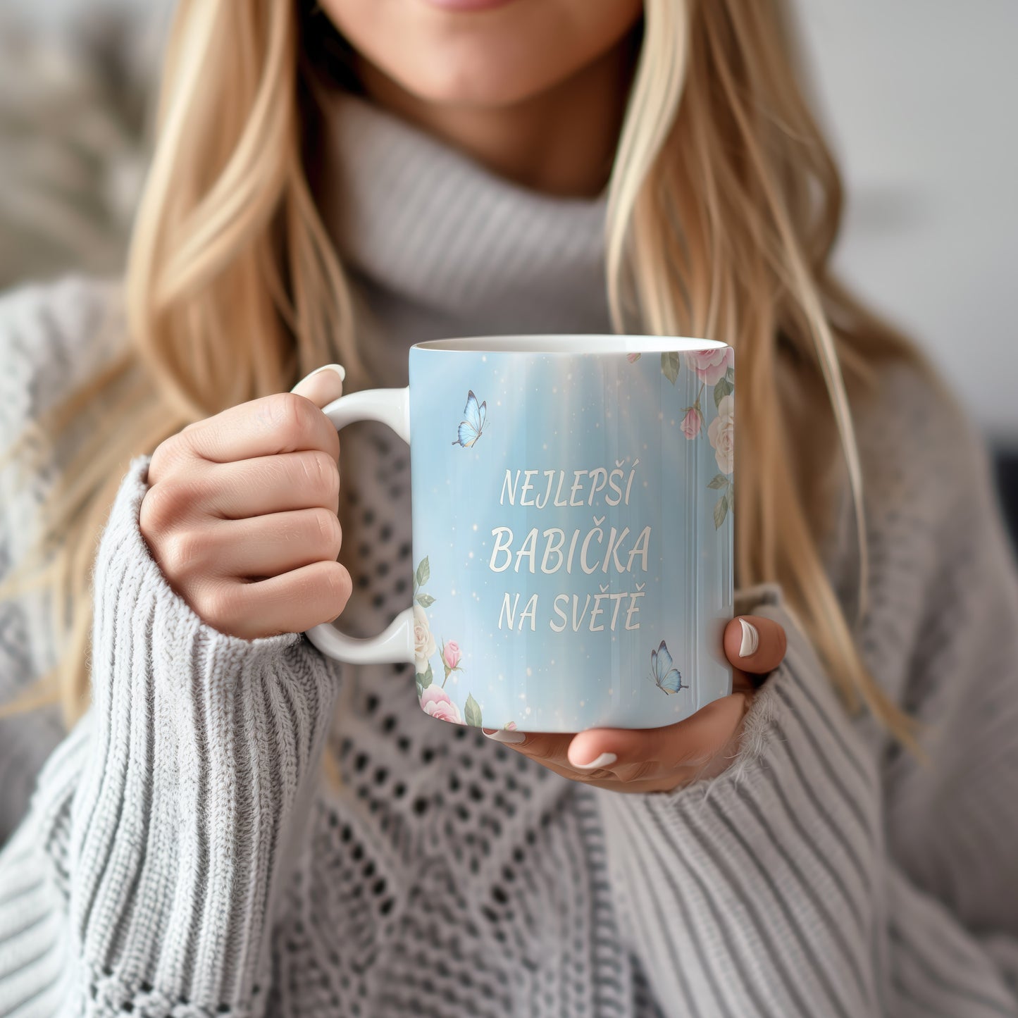 Hrnek s nápisem 'NEJLEPŠÍ BABIČKA NA SVĚTĚ', zdobený motýly a květinami.