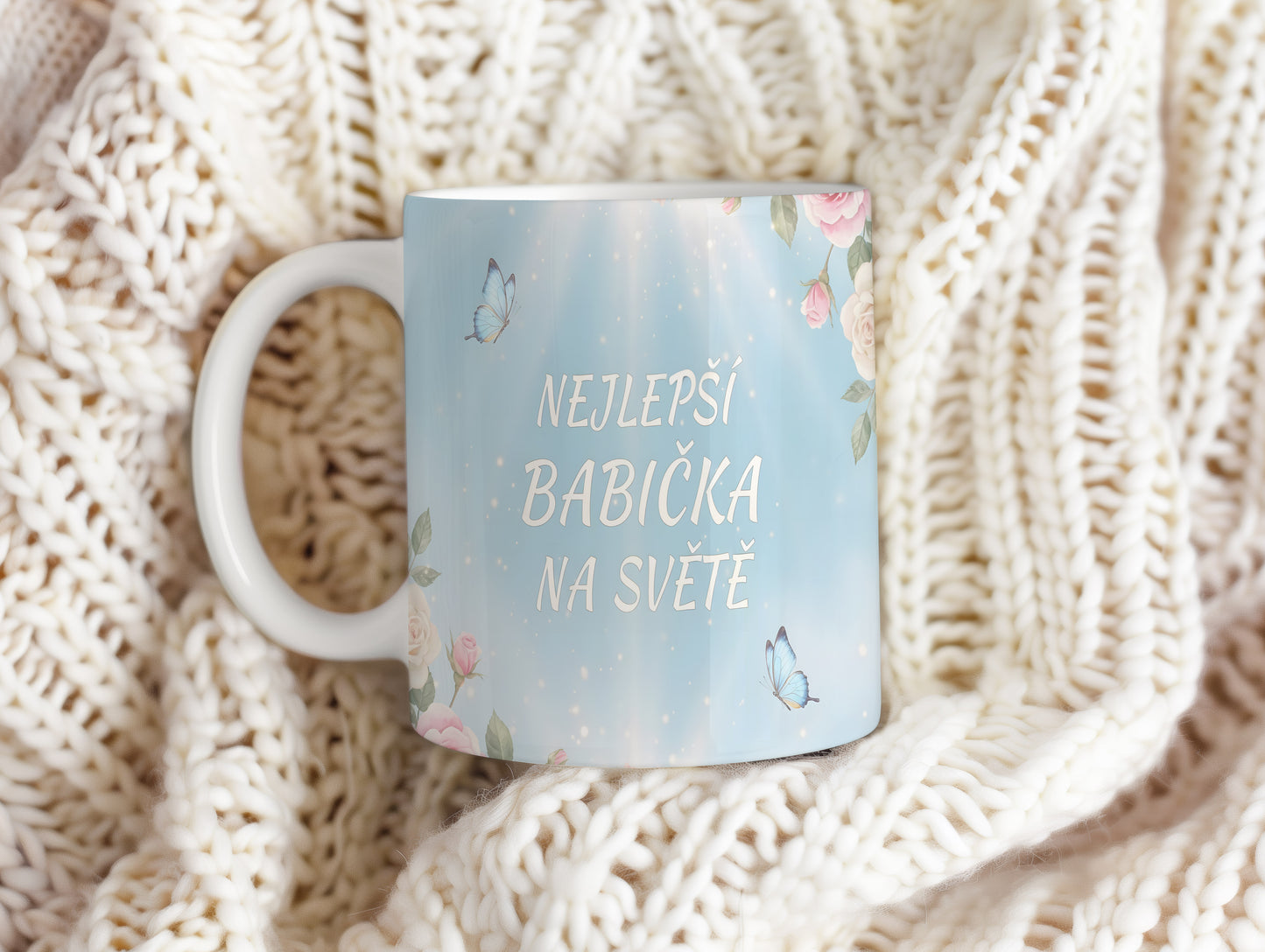 Hrnek s nápisem 'NEJLEPŠÍ BABIČKA NA SVĚTĚ', zdobený motýly a květinami.