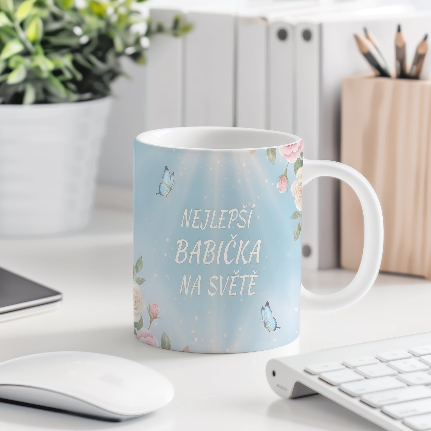 Hrnek s nápisem 'NEJLEPŠÍ BABIČKA NA SVĚTĚ', zdobený motýly a květinami.