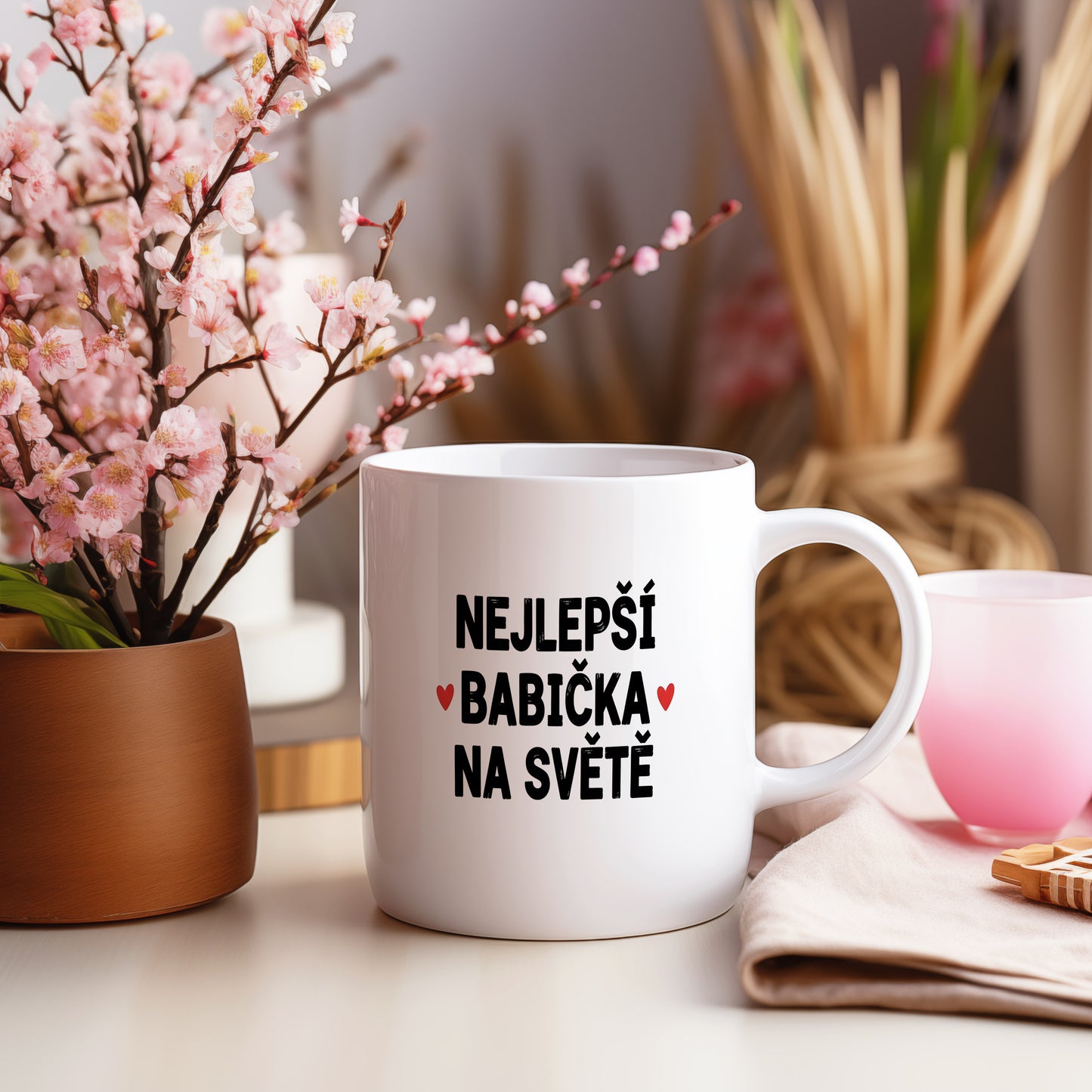 Bílý hrnek s nápisem NEJLEPŠÍ BABIČKA NA SVĚTĚ a červenými srdíčky.