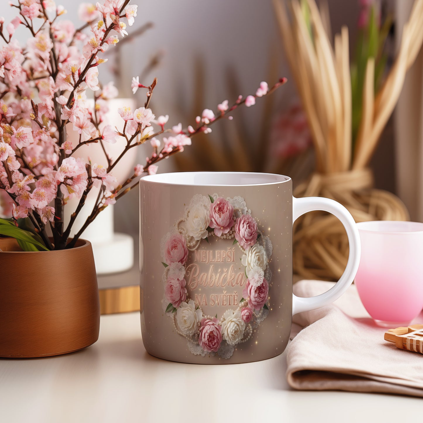Hrnek s nápisem NEJLEPŠÍ BABIČKA NA SVĚTĚ a květinovým věncem.