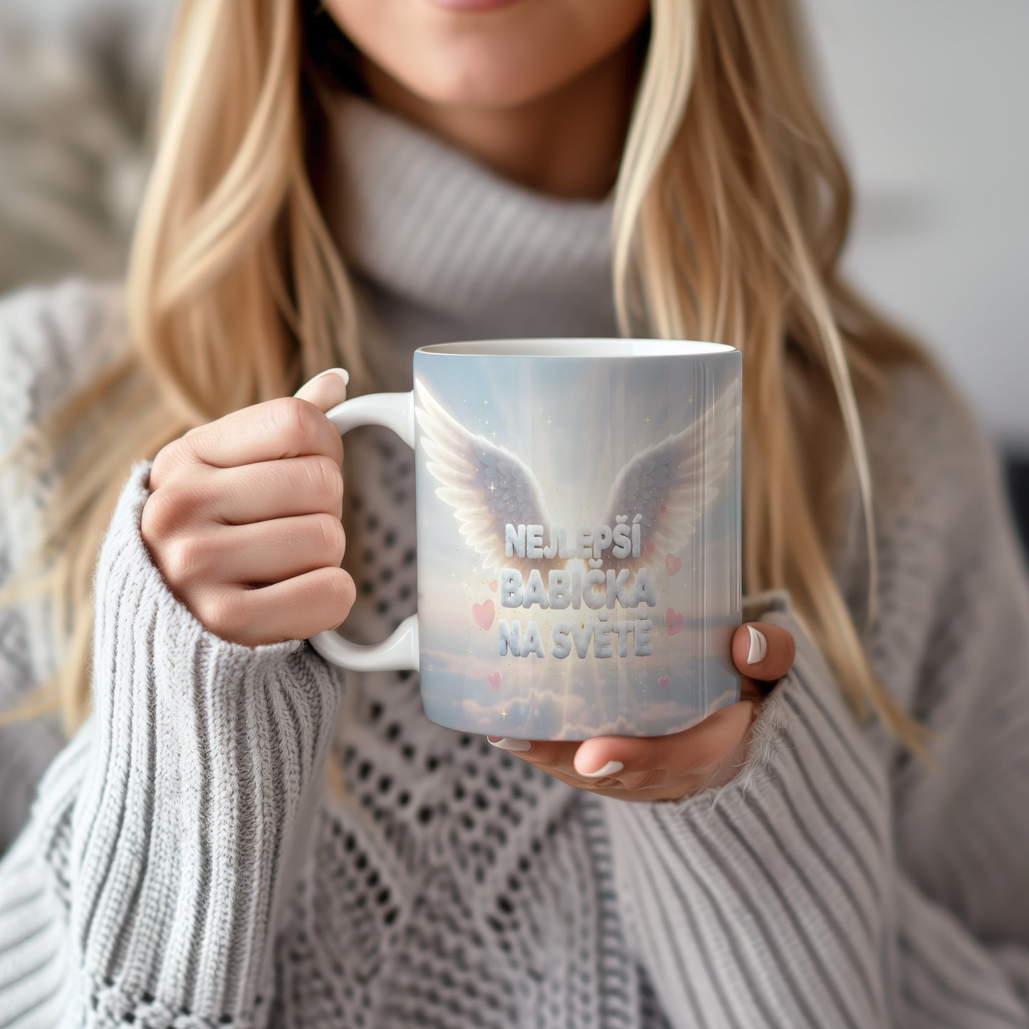 Hrnek s nápisem NEJLEPŠÍ BABIČKA NA SVĚTĚ, křídly a srdíčky na pastelovém pozadí.