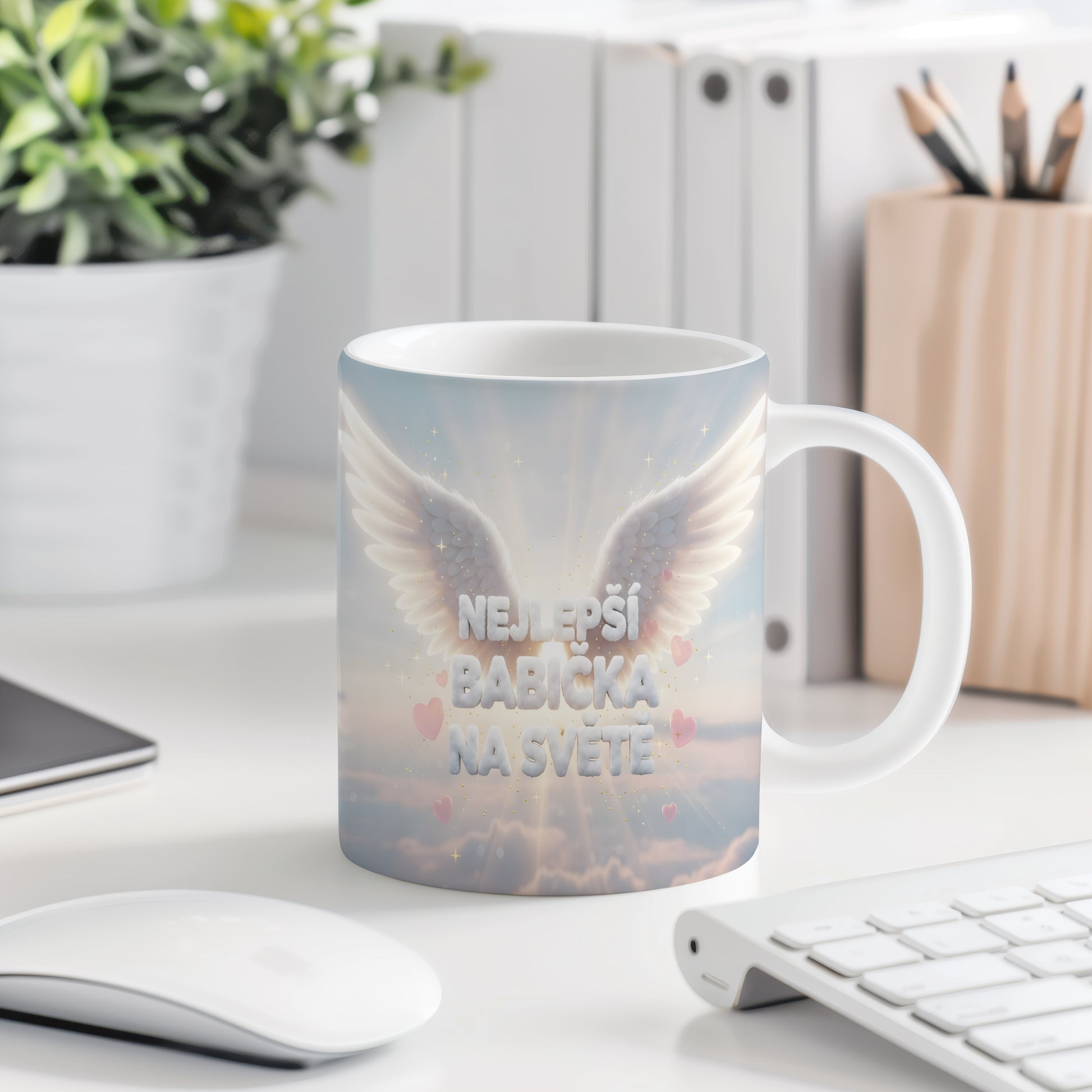 Hrnek s nápisem NEJLEPŠÍ BABIČKA NA SVĚTĚ, křídly a srdíčky na pastelovém pozadí.