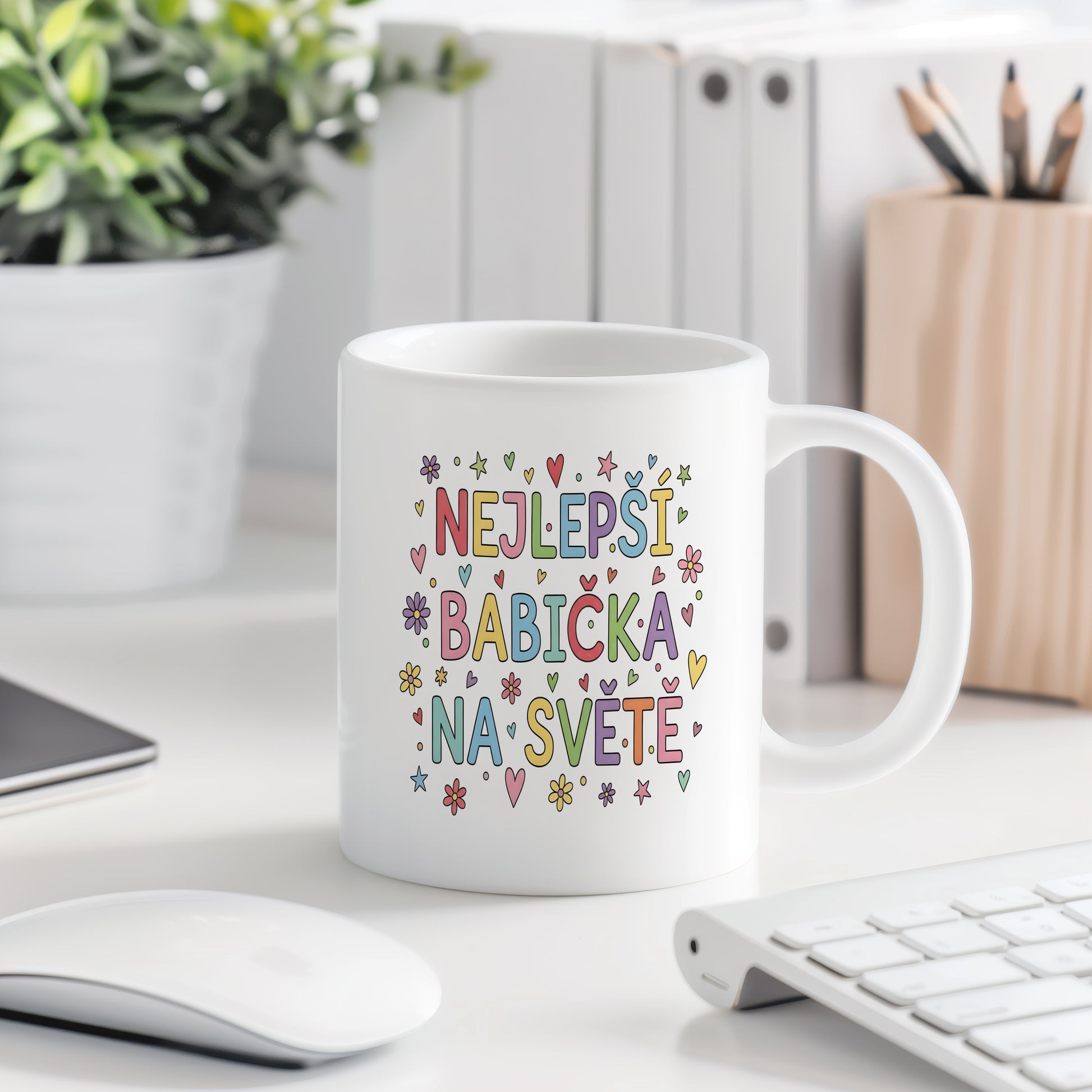 Bílý hrnek s barevnými nápisy, srdci a květinami.