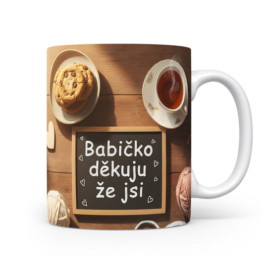 Hrnek s nápisem 'Babičko děkuju že jsi' na dřevěném pozadí s čajem a sušenkami.
