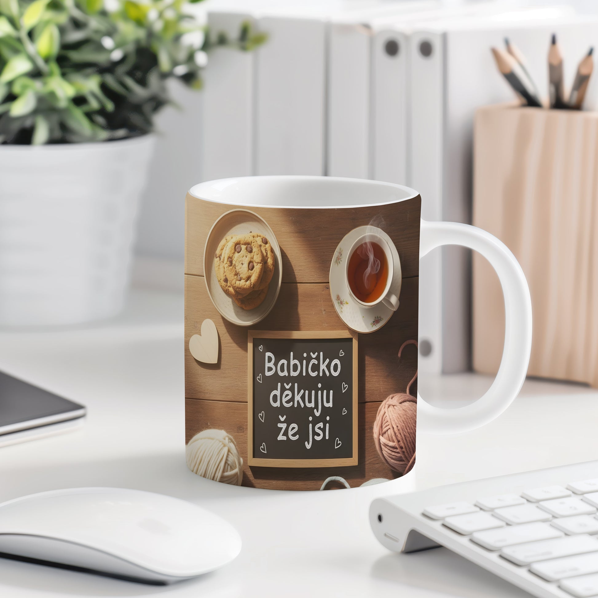 Hrnek s nápisem 'Babičko děkuju že jsi' na dřevěném pozadí s čajem a sušenkami.
