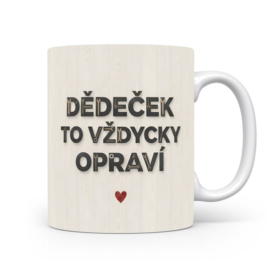 Bílý hrnek s nápisem 'DĚDEČEK TO VŽDYCKY OPRAVÍ' a červeným srdcem na dřevěném pozadí.