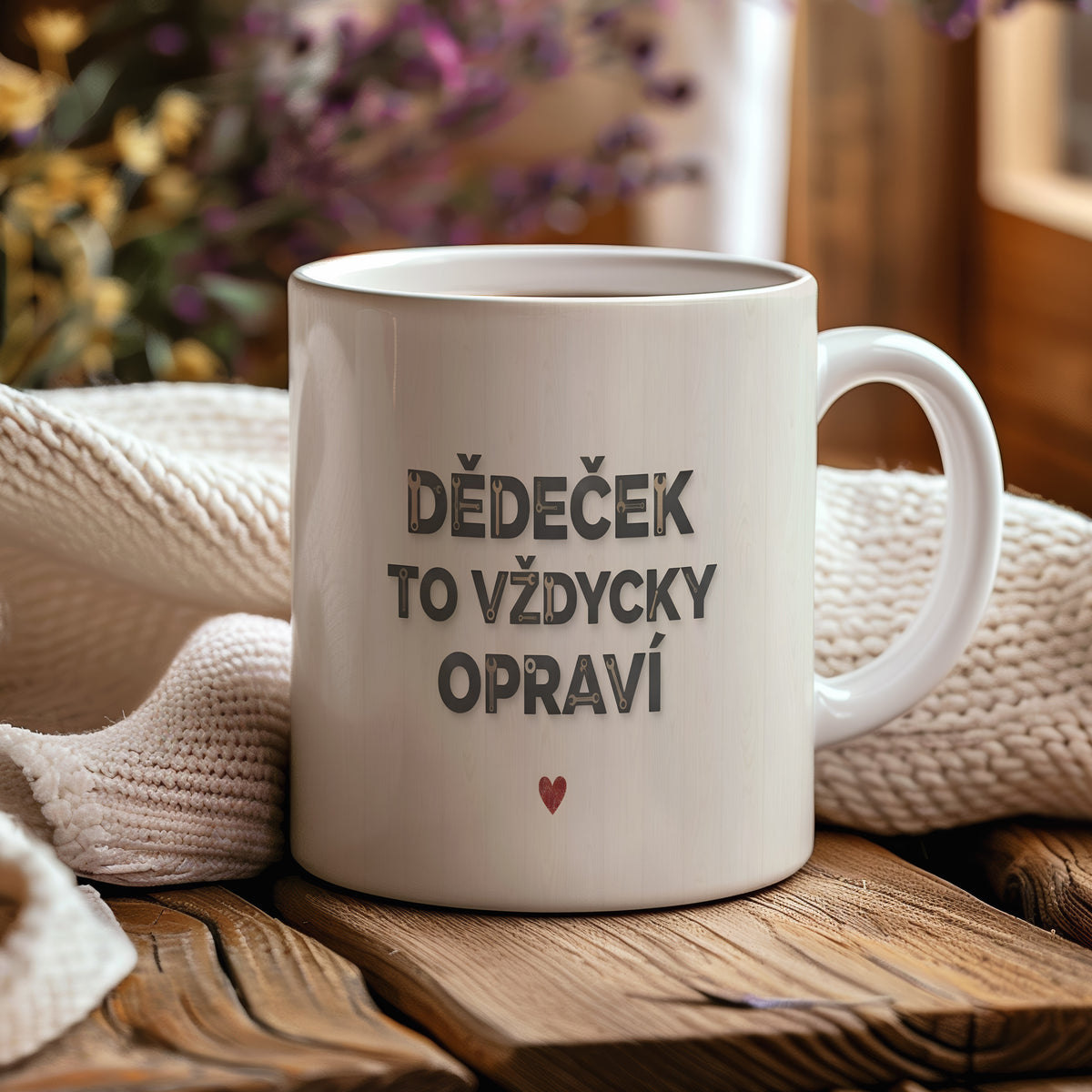 Bílý hrnek s nápisem 'DĚDEČEK TO VŽDYCKY OPRAVÍ' a červeným srdcem na dřevěném pozadí.