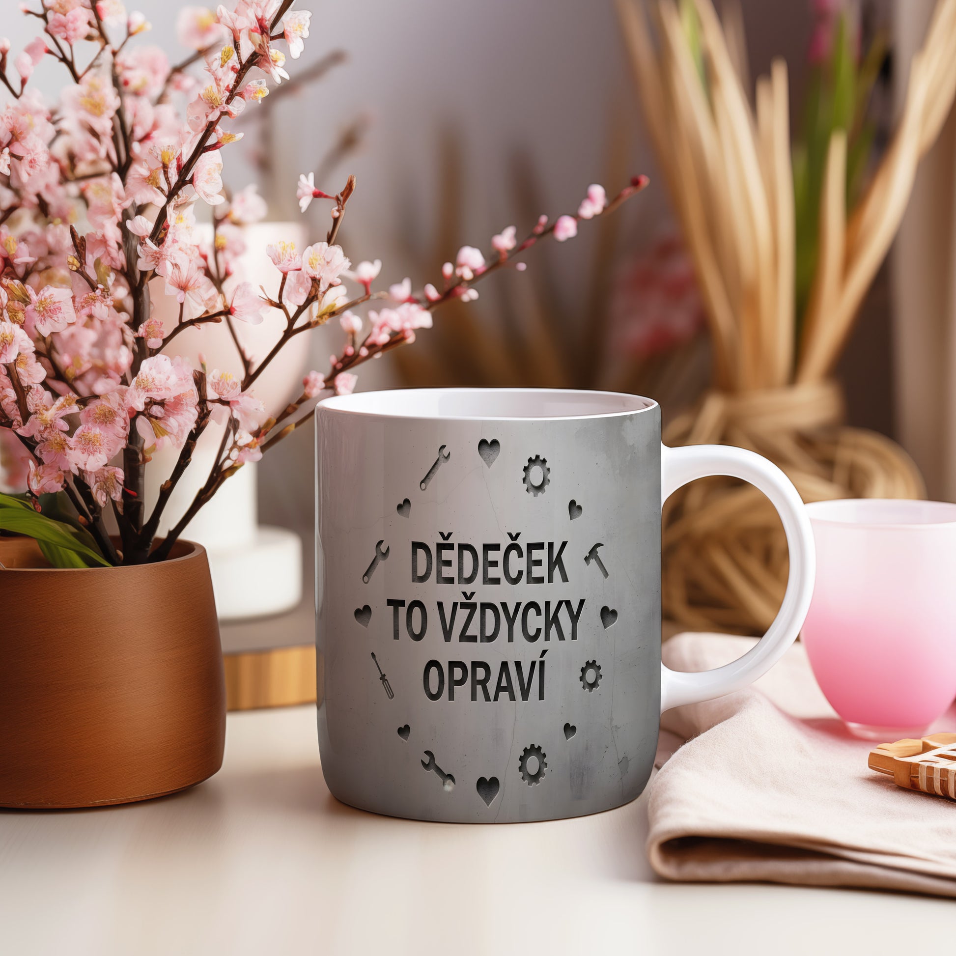 Hrnek s nápisem 'DĚDEČEK TO VŽDYCKY OPRAVÍ' a motivem nářadí na betonovém pozadí.