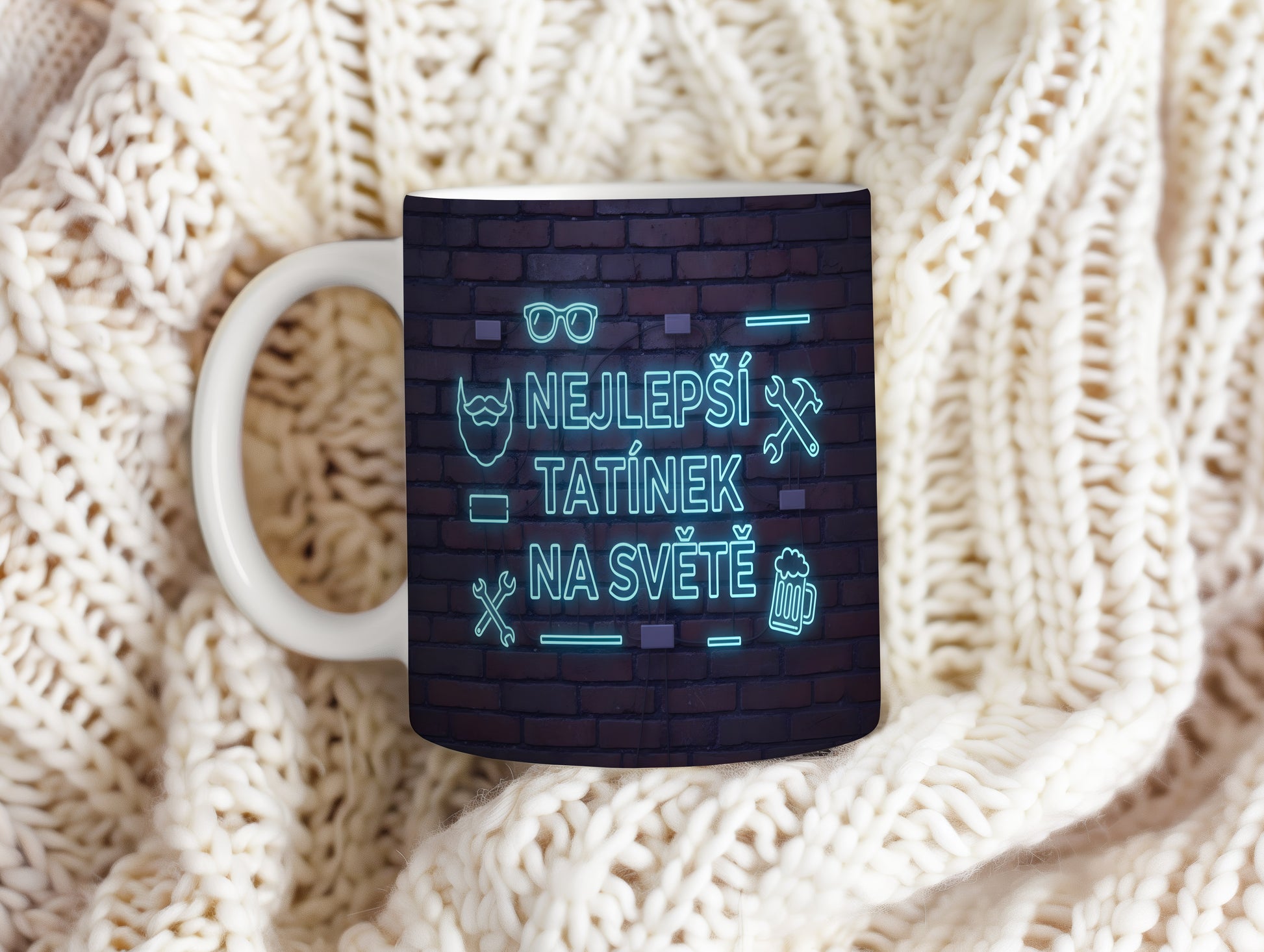 Hrnek s neonovým nápisem 'NEJLEPŠÍ TATÍNEK NA SVĚTĚ' na cihlovém pozadí.