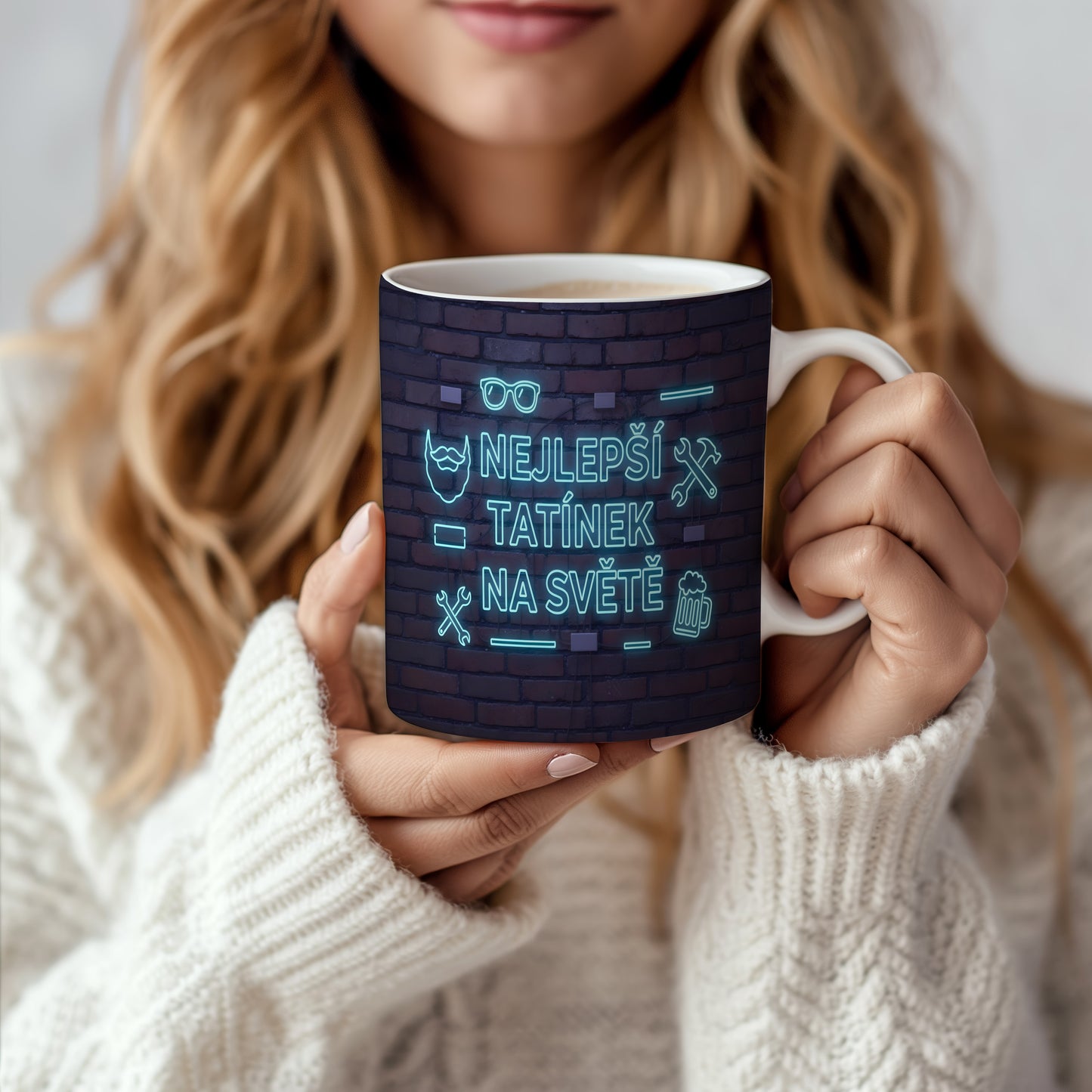 Hrnek s neonovým nápisem 'NEJLEPŠÍ TATÍNEK NA SVĚTĚ' na cihlovém pozadí.