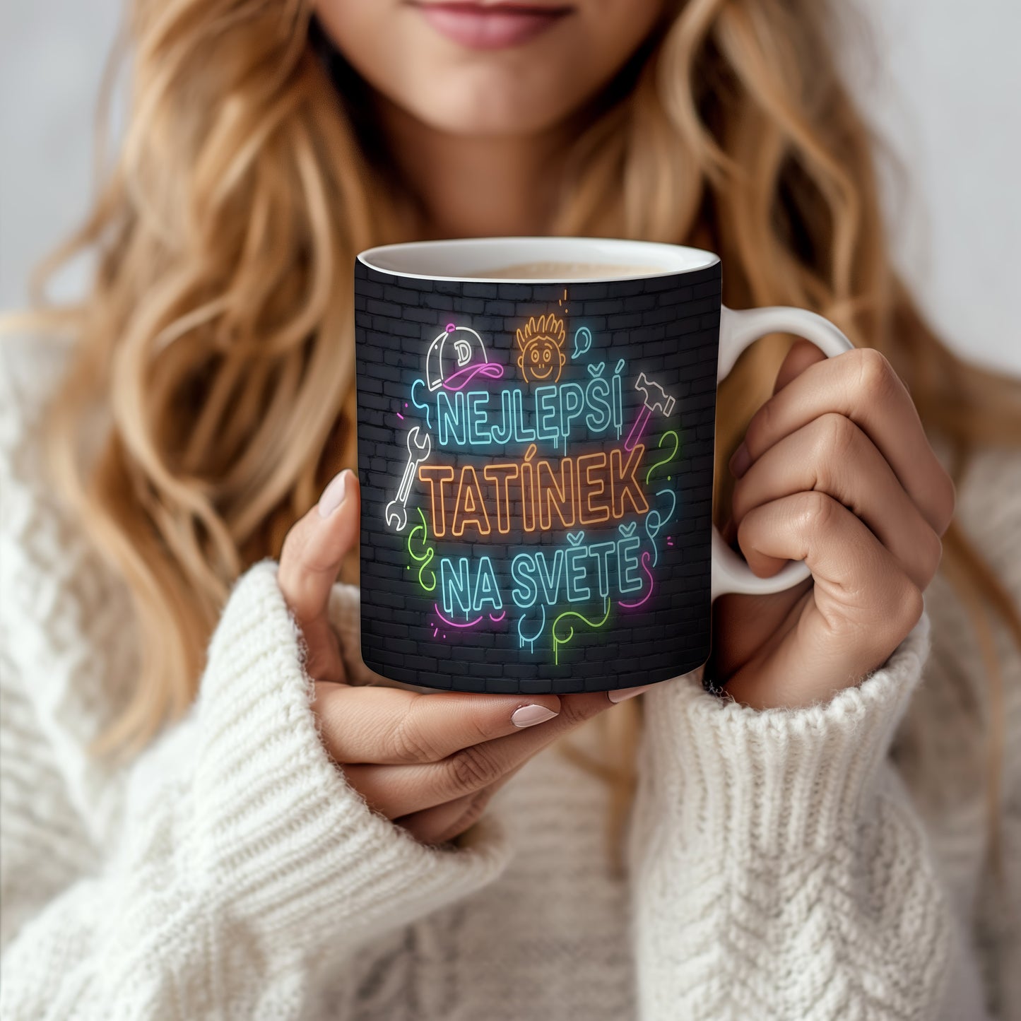 Hrnek s neonovým nápisem NEJLEPŠÍ TATÍNEK NA SVĚTĚ na cihlovém pozadí.