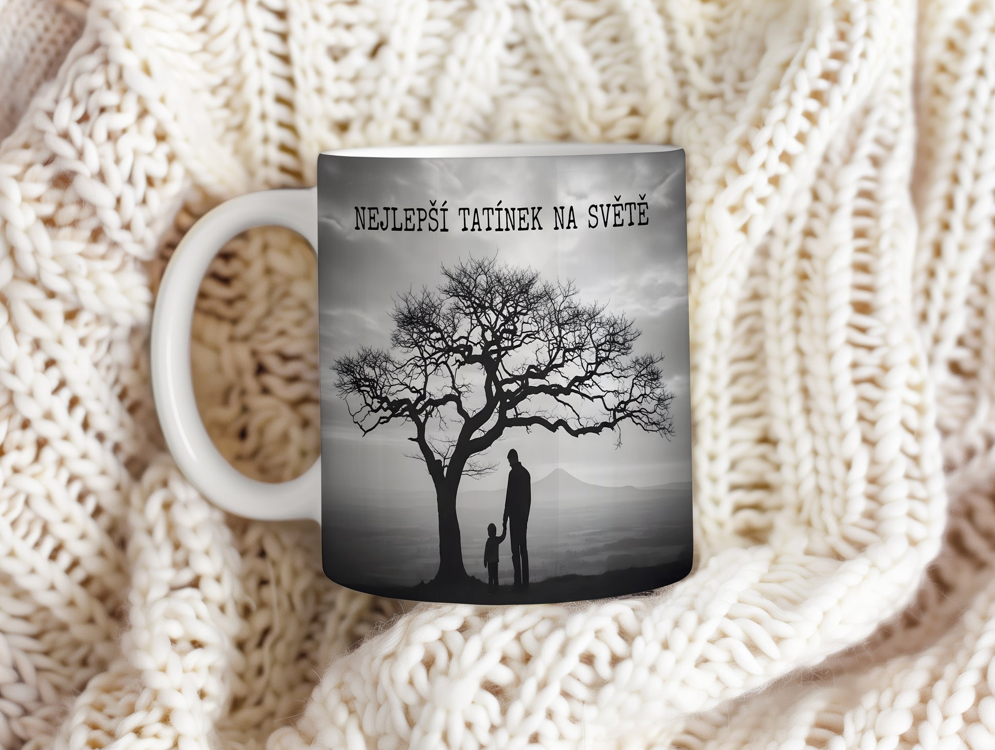 Hrnek s černobílou siluetou otce a dítěte pod stromem.