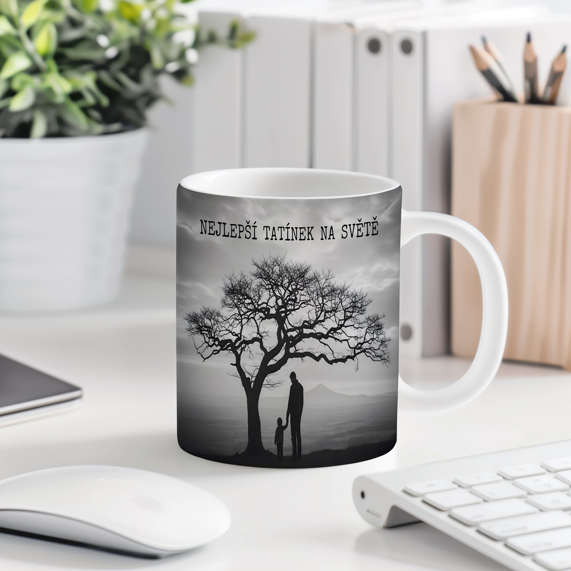 Hrnek s černobílou siluetou otce a dítěte pod stromem.