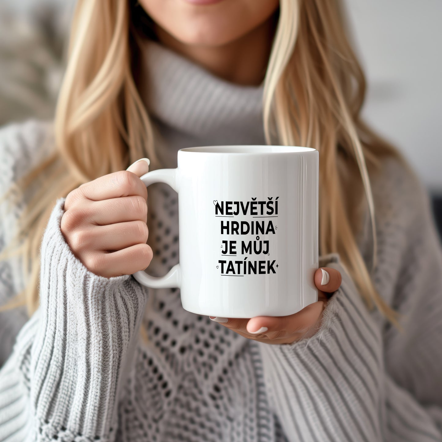 Bílý hrnek s černým nápisem 'NEJVĚTŠÍ HRDINA JE MŮJ TATÍNEK' a malými srdíčky.