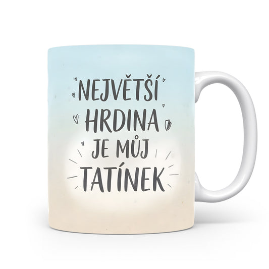 Hrnek s nápisem 'NEJVĚTŠÍ HRDINA JE MŮJ TATÍNEK' na modrém pozadí.